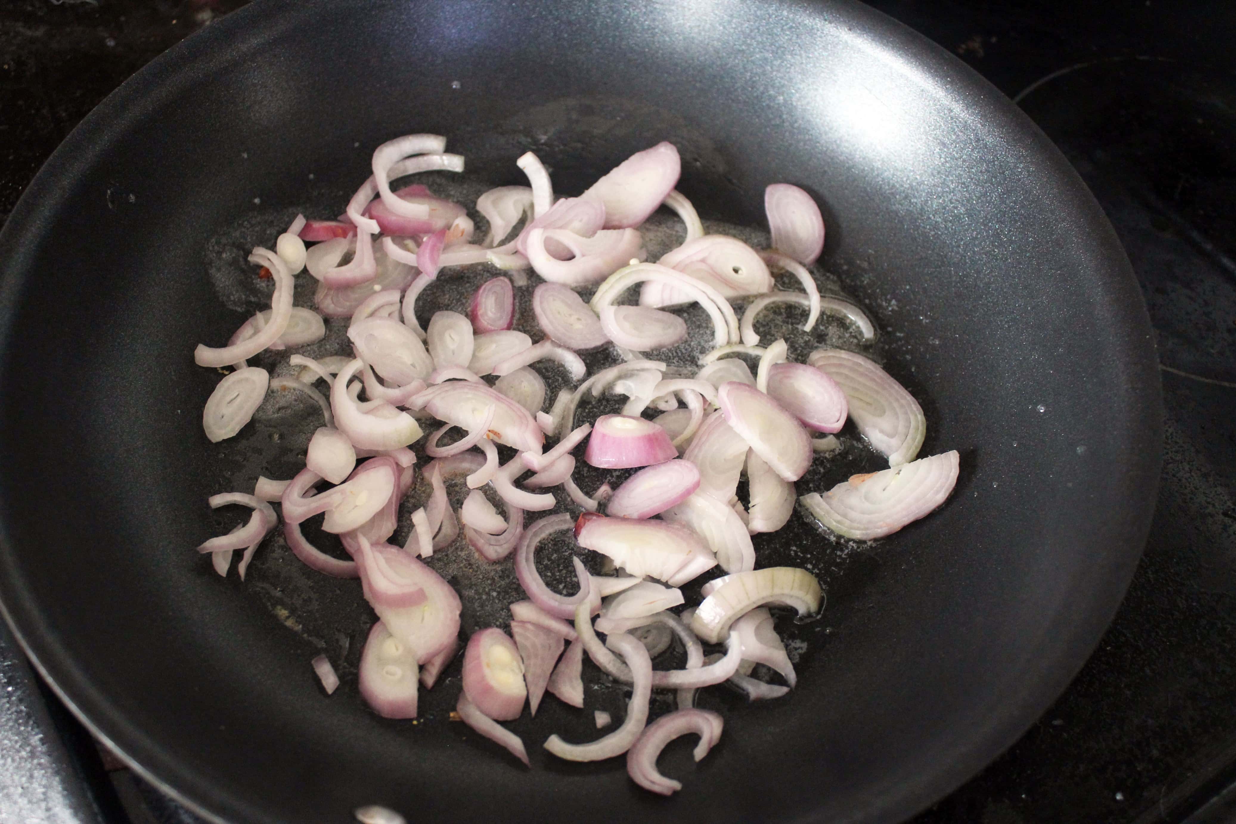 sliced shallots in a black skillet with butter.