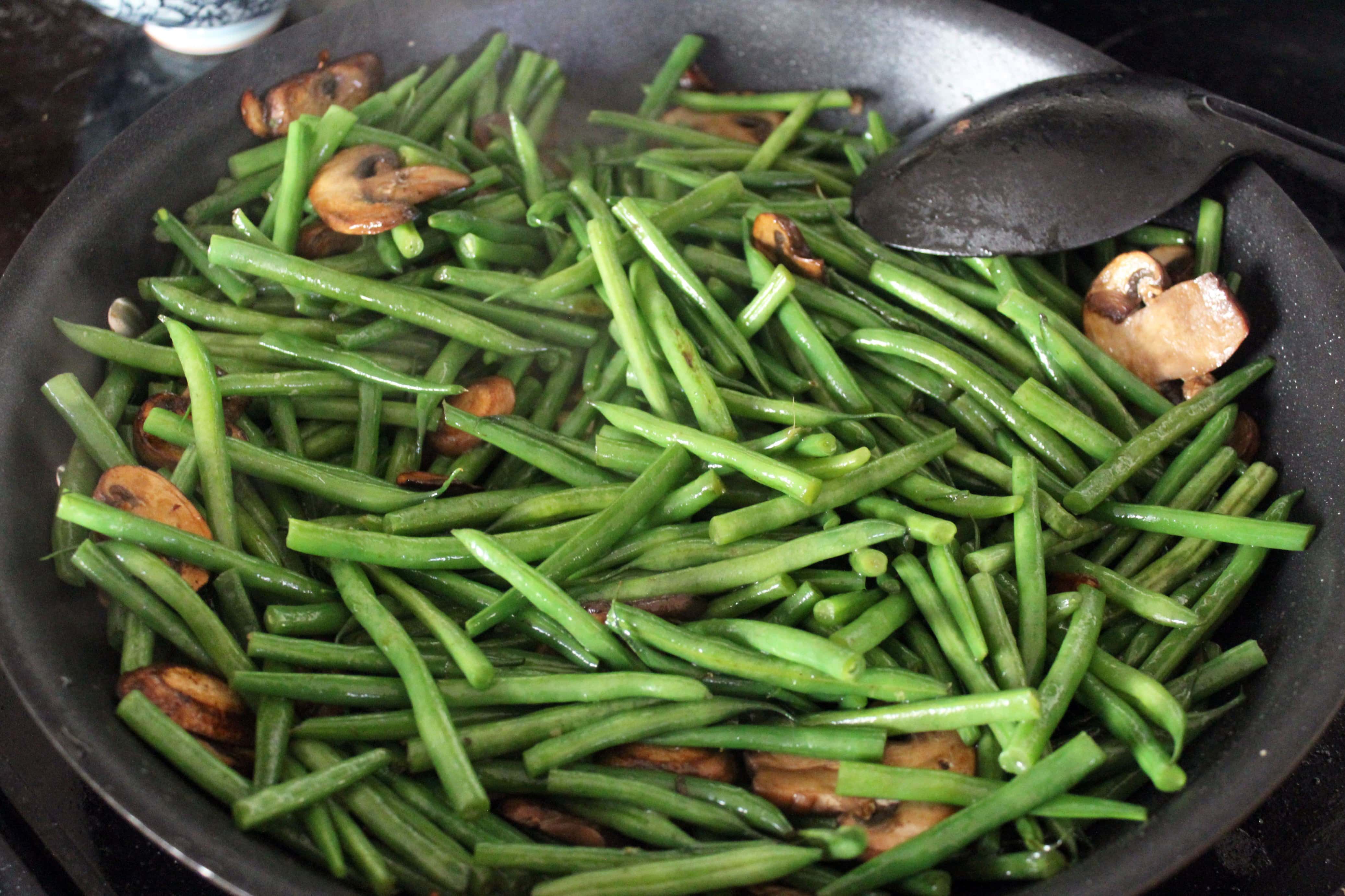 green beans and mushrooms in a large black skillet.