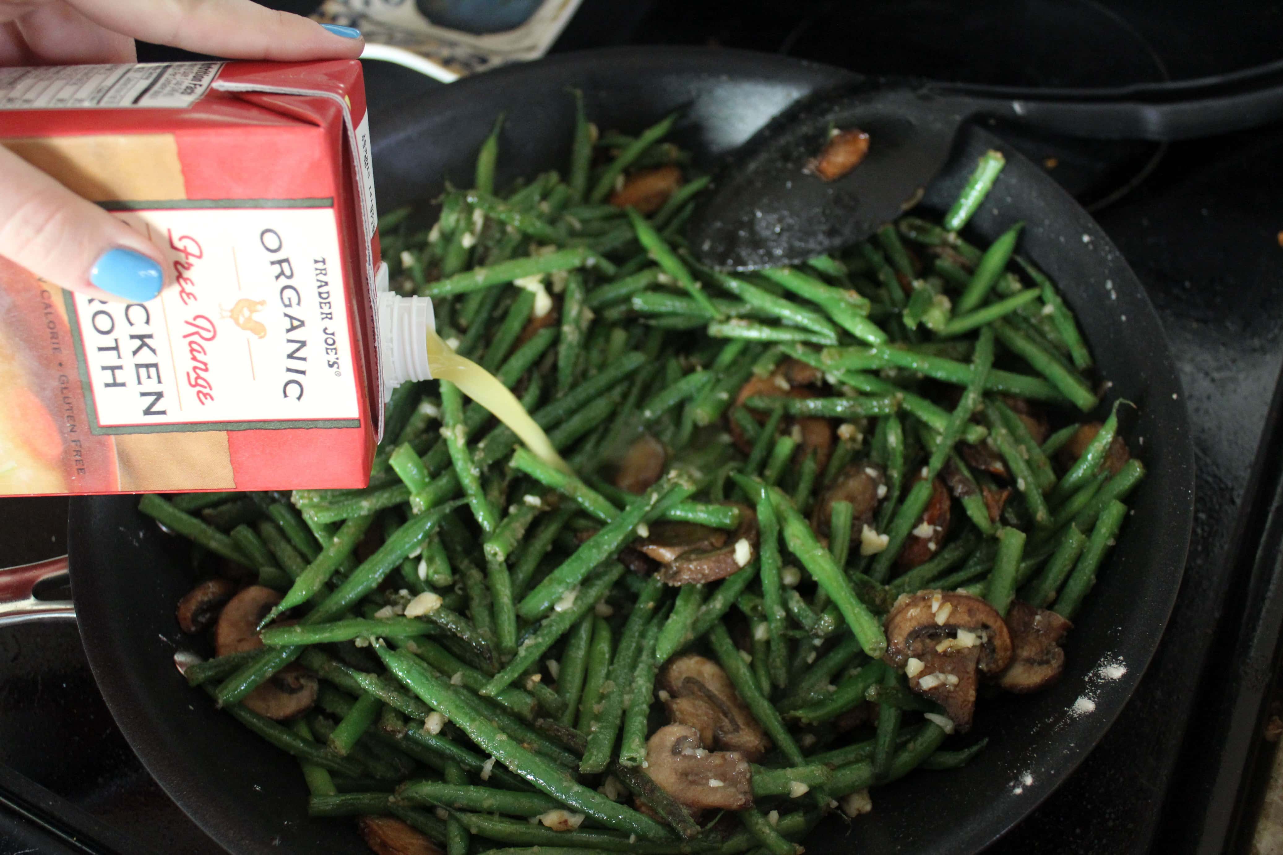stock being poured into a skillet of green beans.