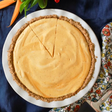 Top view of pumpkin pie with graham cracker crust with one slice taken out.