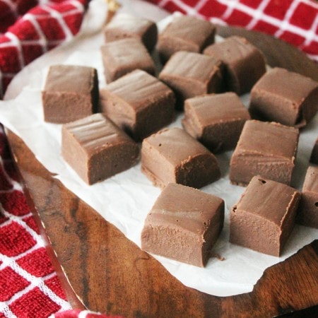 squares of 2 ingredient mint fudge on parchment paper with a red checked napkin.