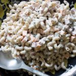 flat bowl of southern macaroni salad with ham and cheese and silver serving spoon