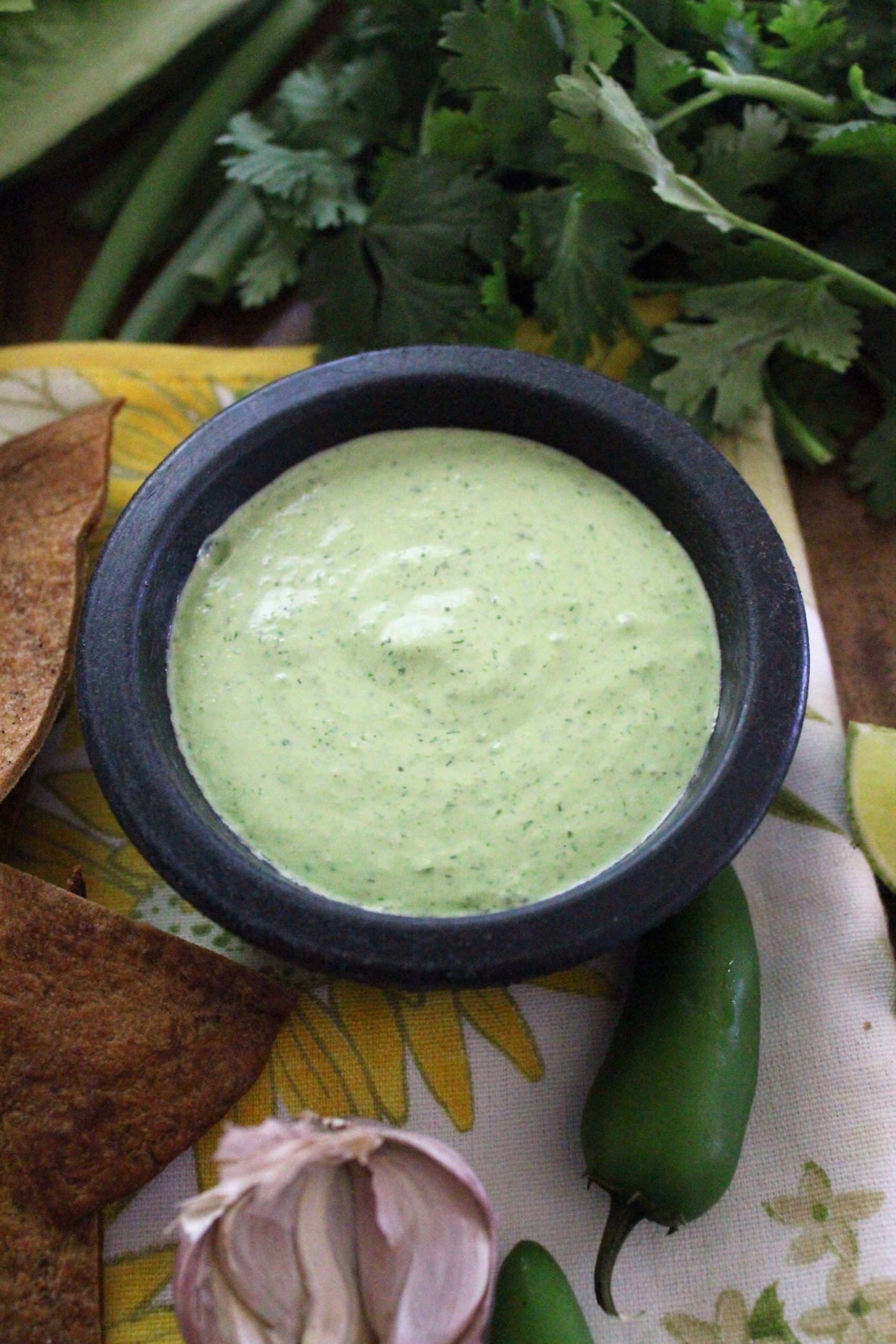 small black bowl of jalapeno ranch dressing on yellow floral napkin.