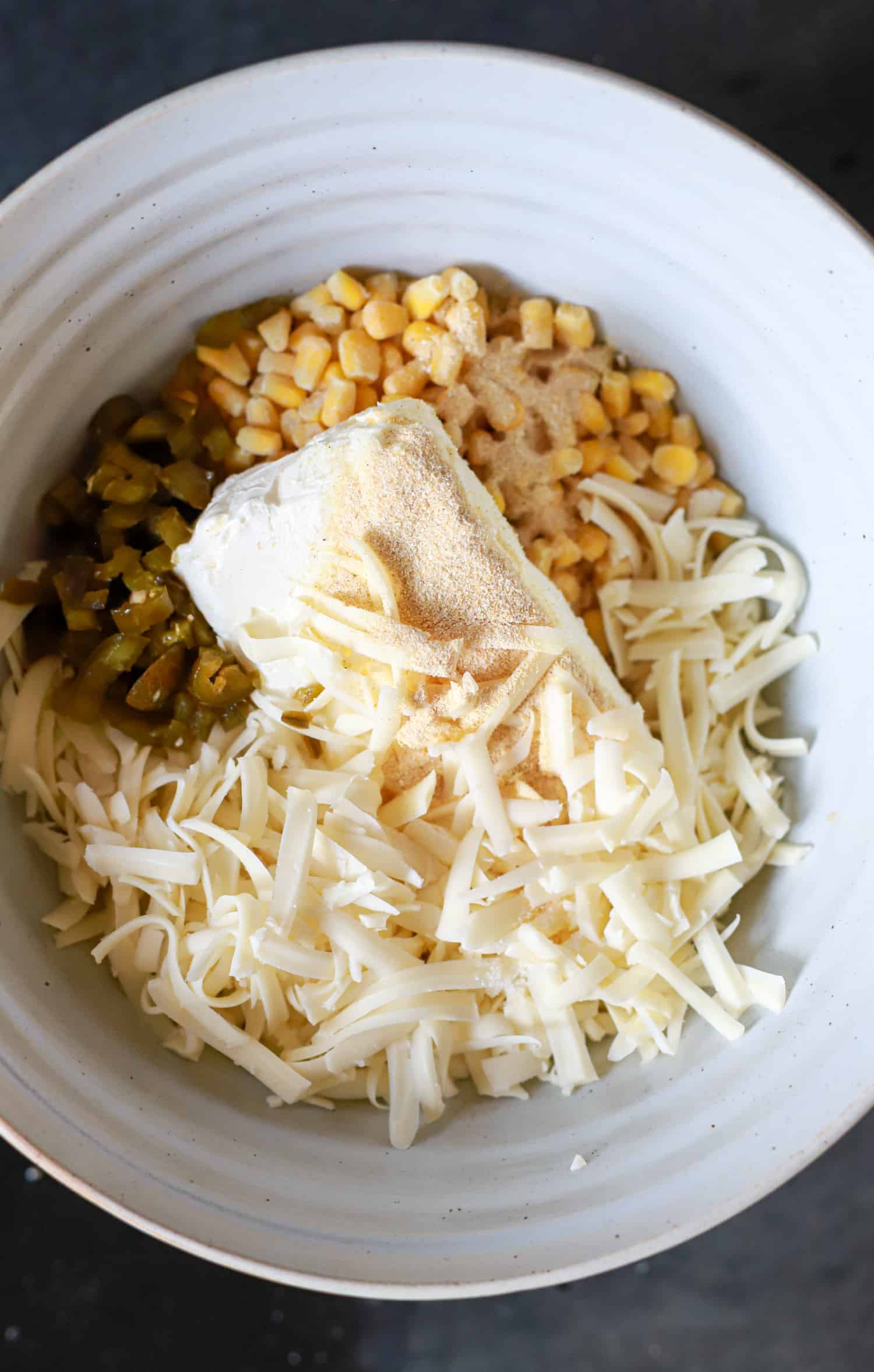 white bowl with ingredients for frozen corn dip.