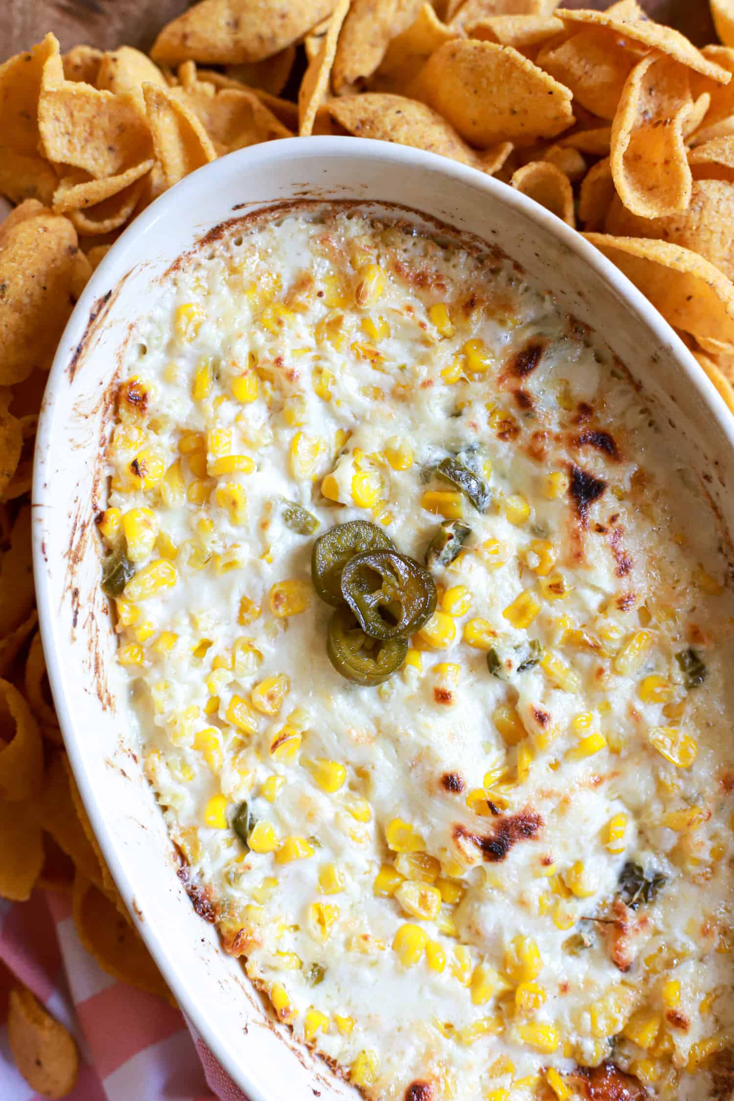 oval baking diwh with cheesy corn dip topped with pickled jalapenos.