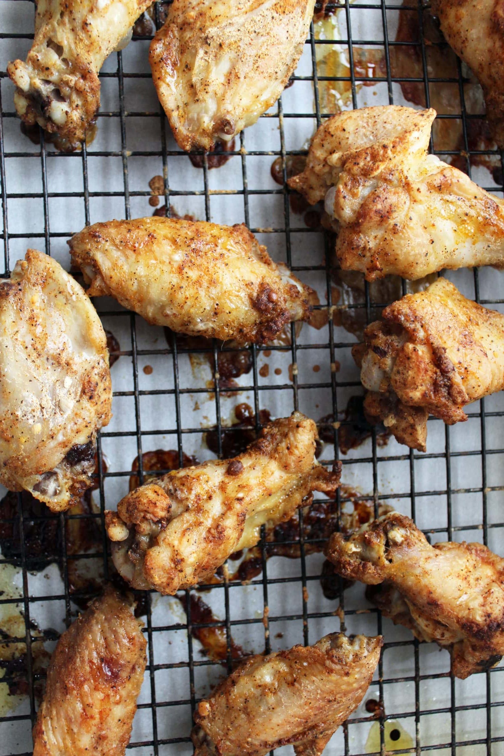 crispy baked chicken wings on wire rack and white parchment paper.