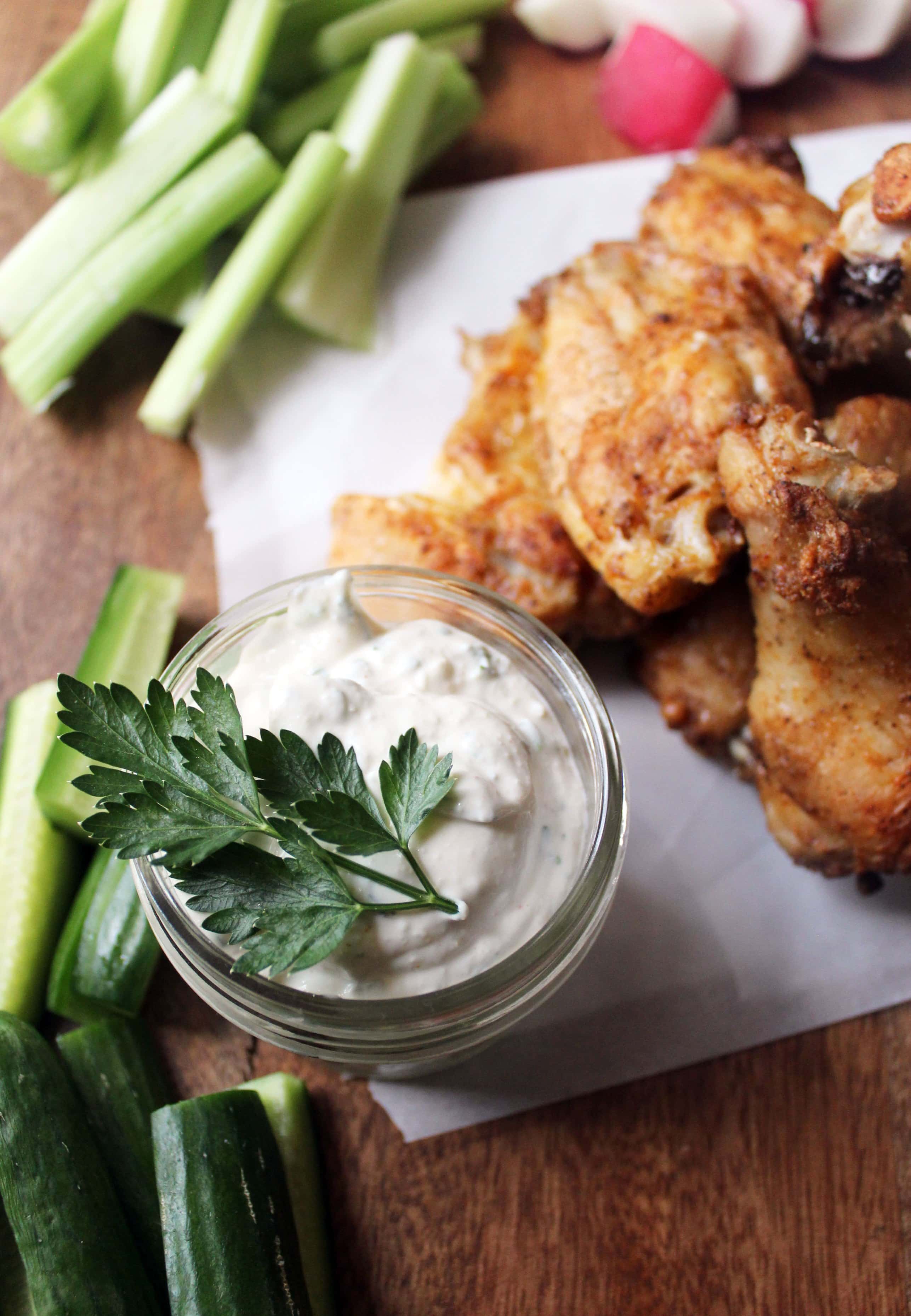 wood platter with baked wings, raw veggies, and blue cheese ranch dip.