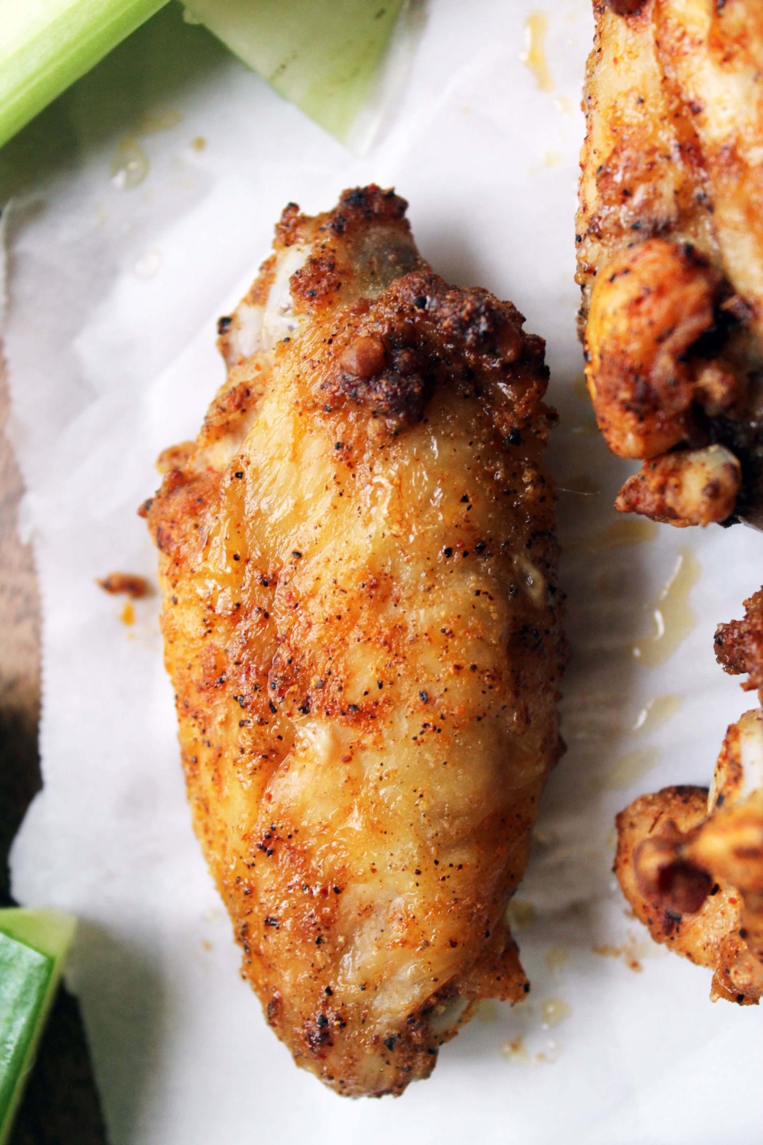 single baked chicken wing with homemade dry rub on white parchment paper.