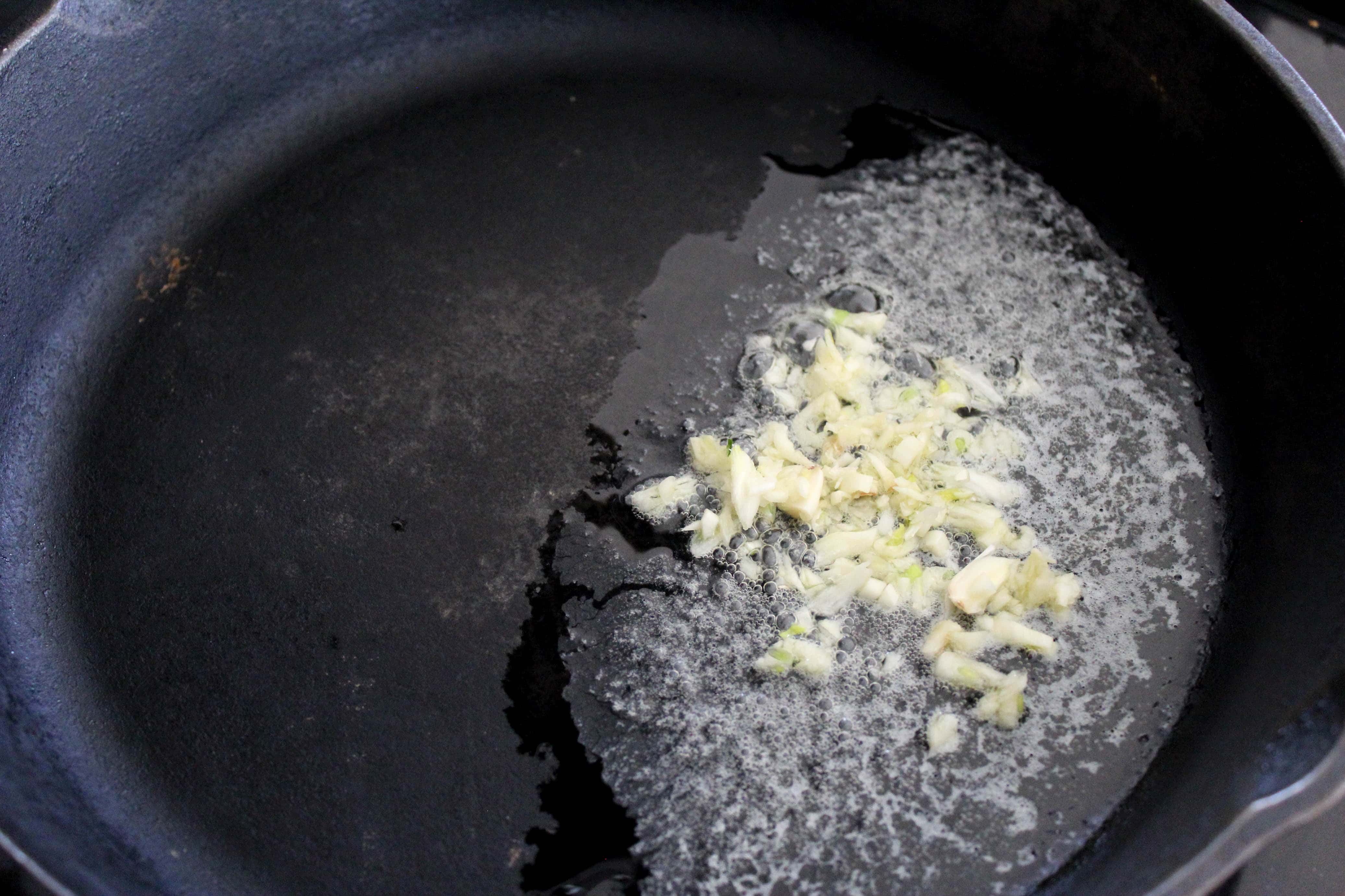 Melted butter and garlic in a shallow black skillet.