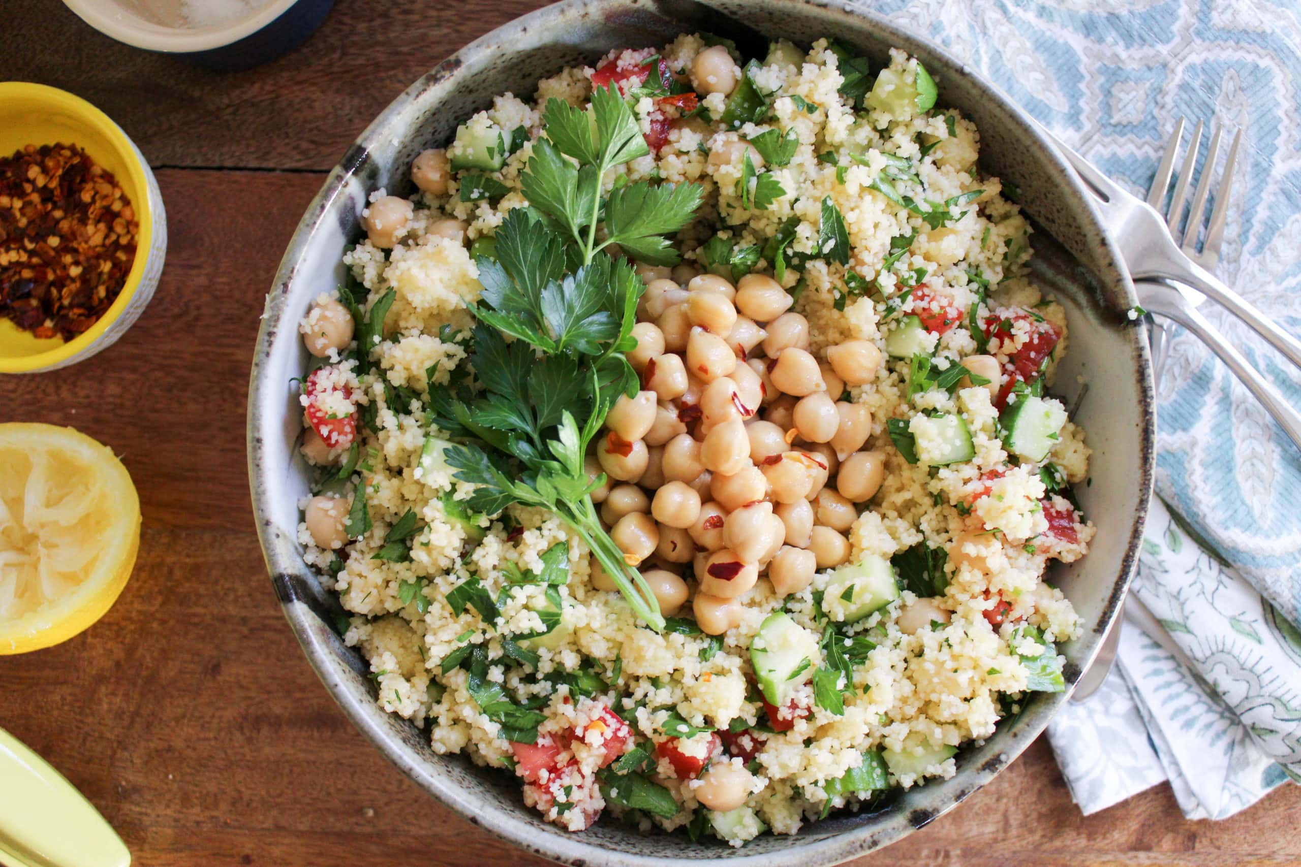 gray pottery bowl of vegan tabouli salad topped with parsley and marinated garbanzo beans with blue napkins