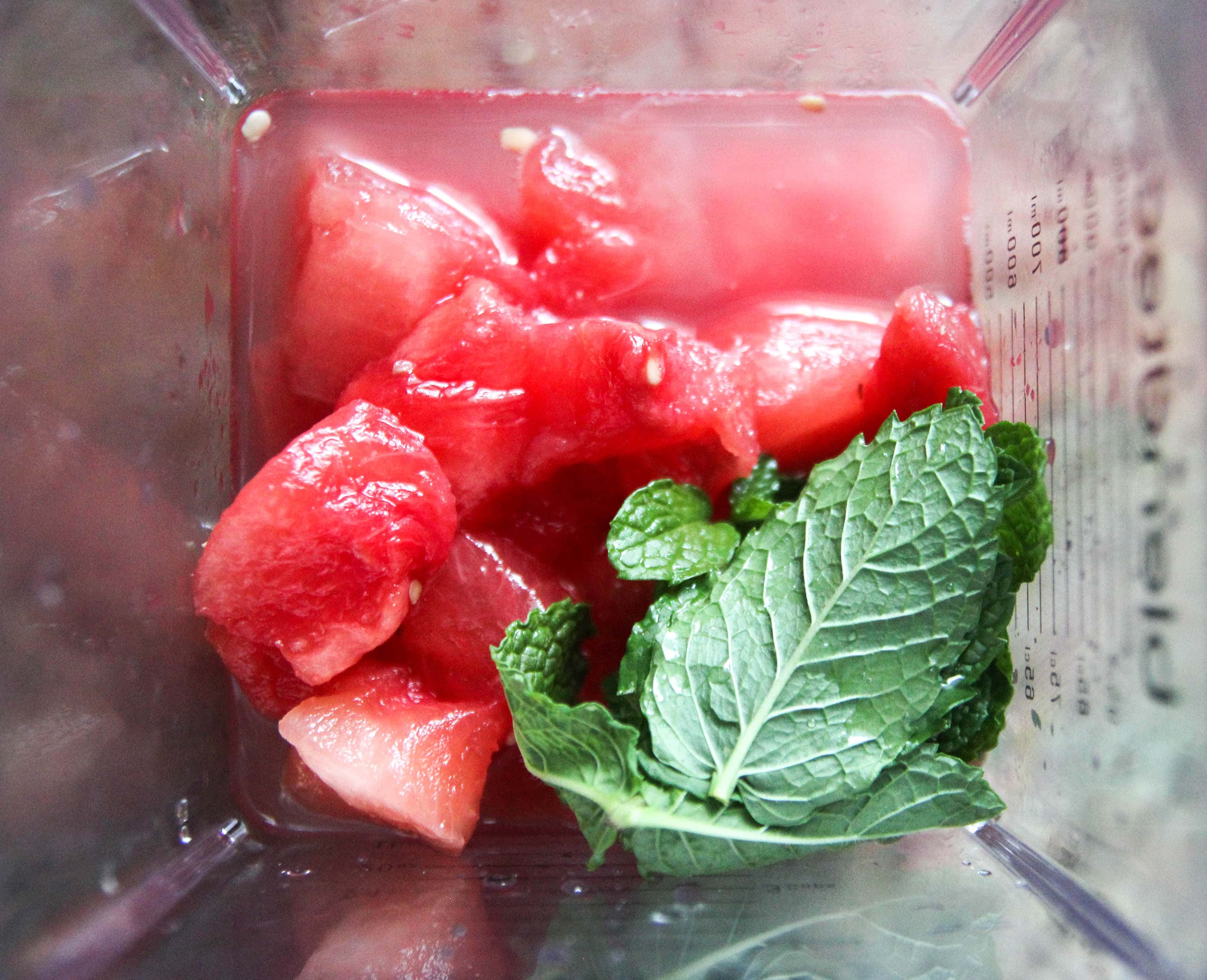 Top view of watermelon chunks and mint leaves in blender