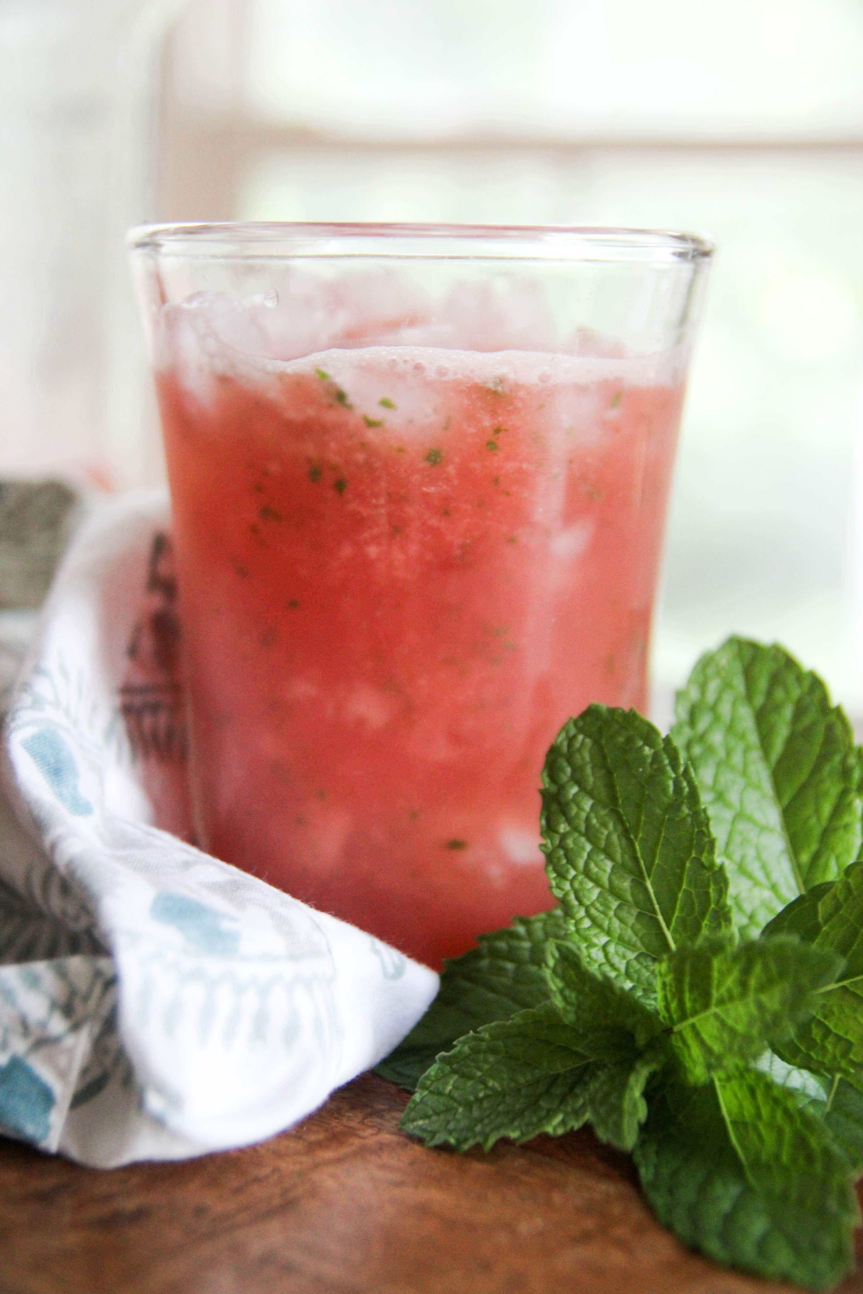 top view of glass of watermelon aqua fresca with napkin and mint leaves