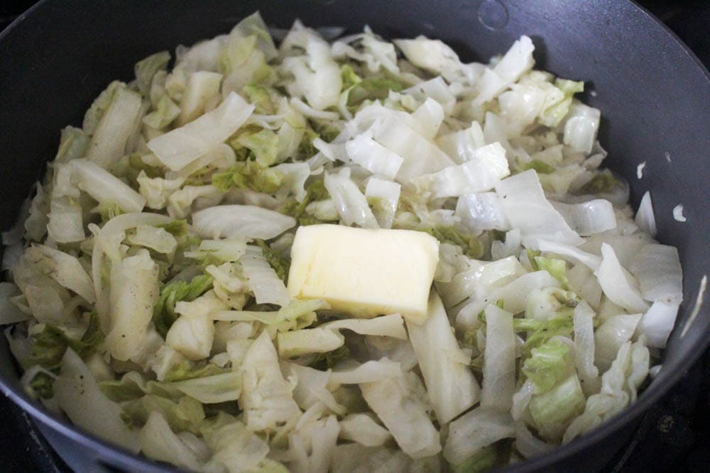 Pat of butter in a skillet with cooked cabbage.