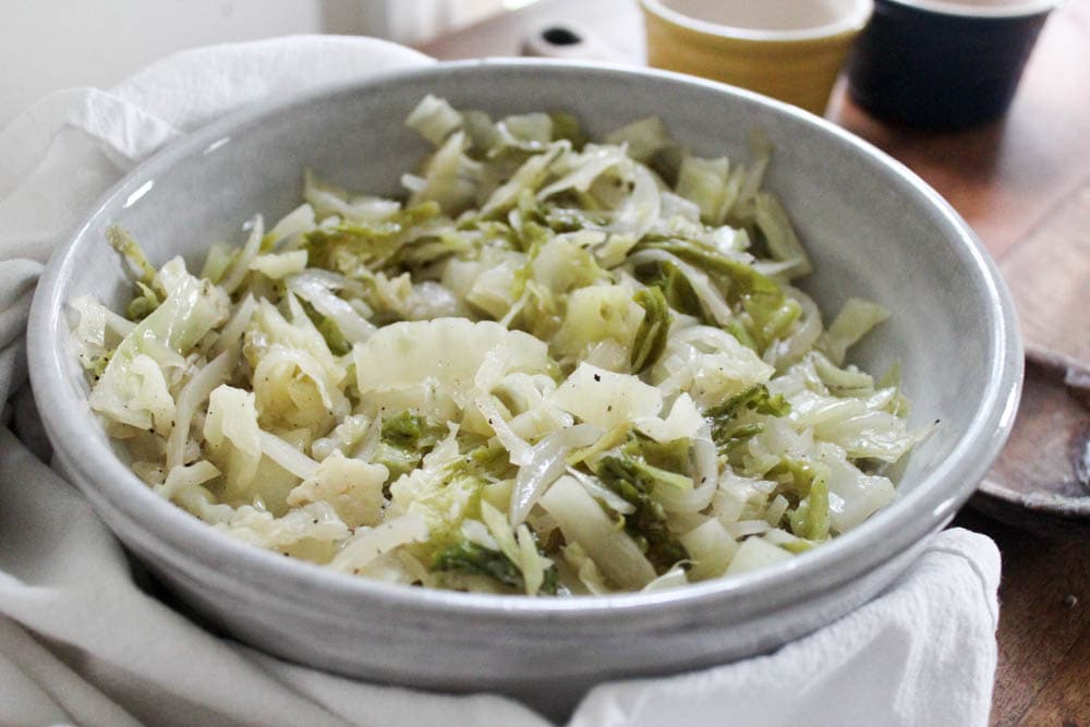 Gray bowl of stewed cabbage on a white napkin.