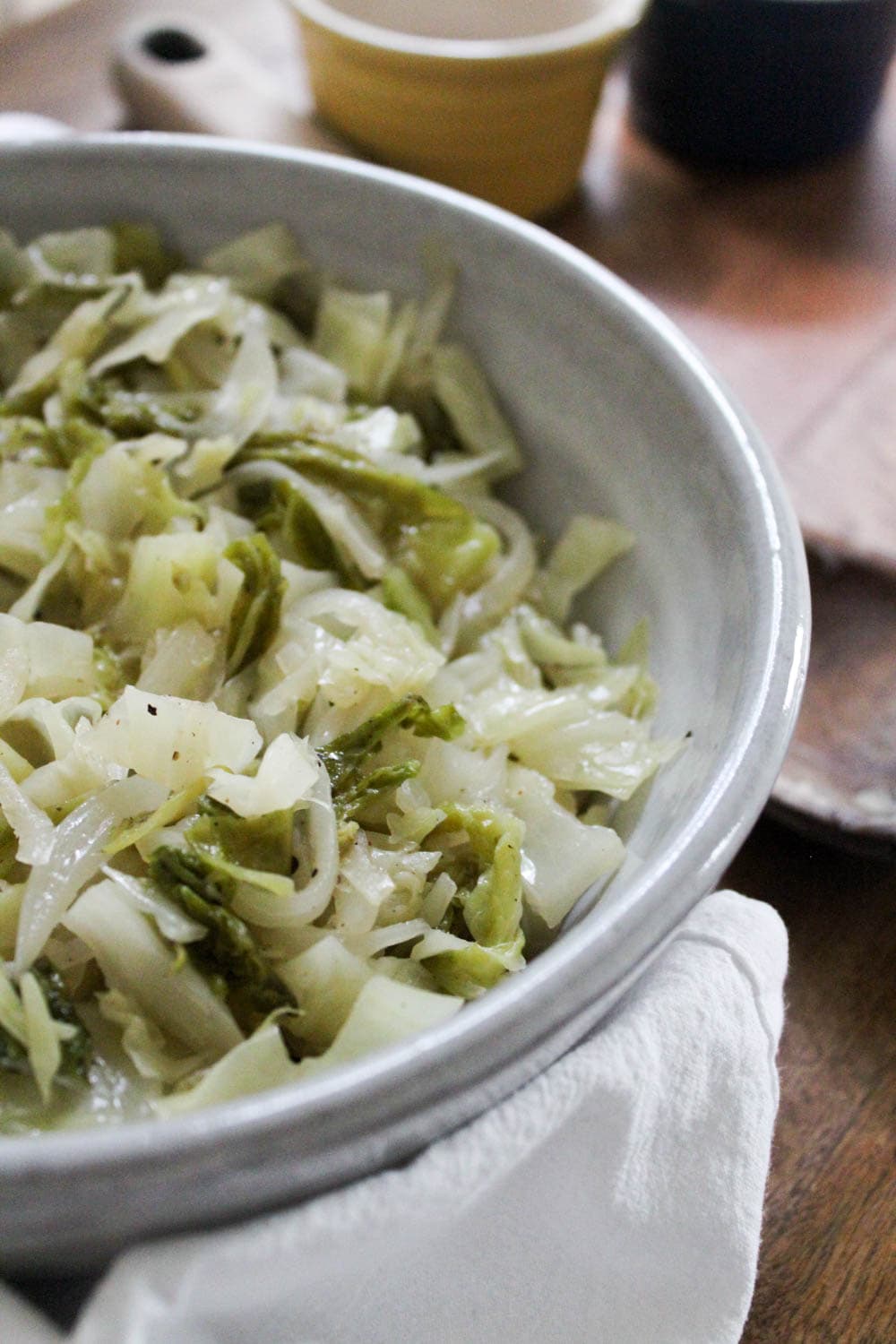 Bowl of buttered cabbage on serving board.