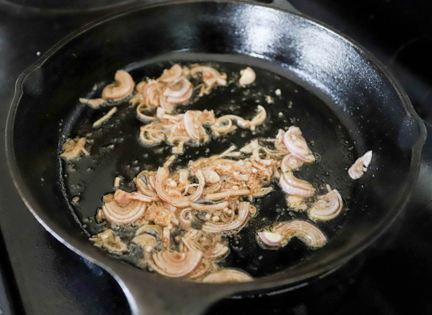 shallots sizzling in black cast iron skillet