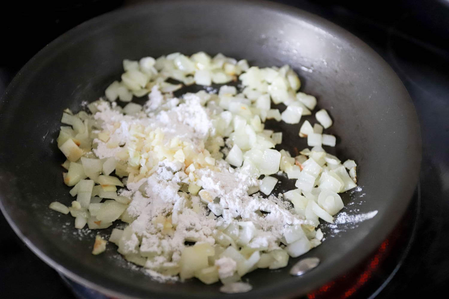 black skillet with sautéed onions, garlic, and flour.