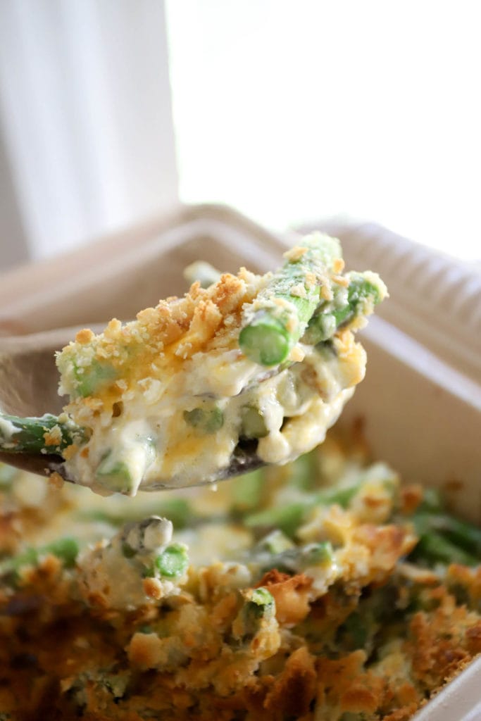 spoonful of fresh asparagus casserole in front of window.
