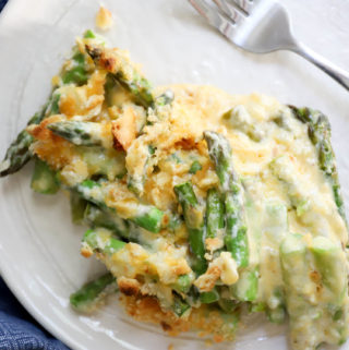 white plate of asparagus casserole with a silver fork.