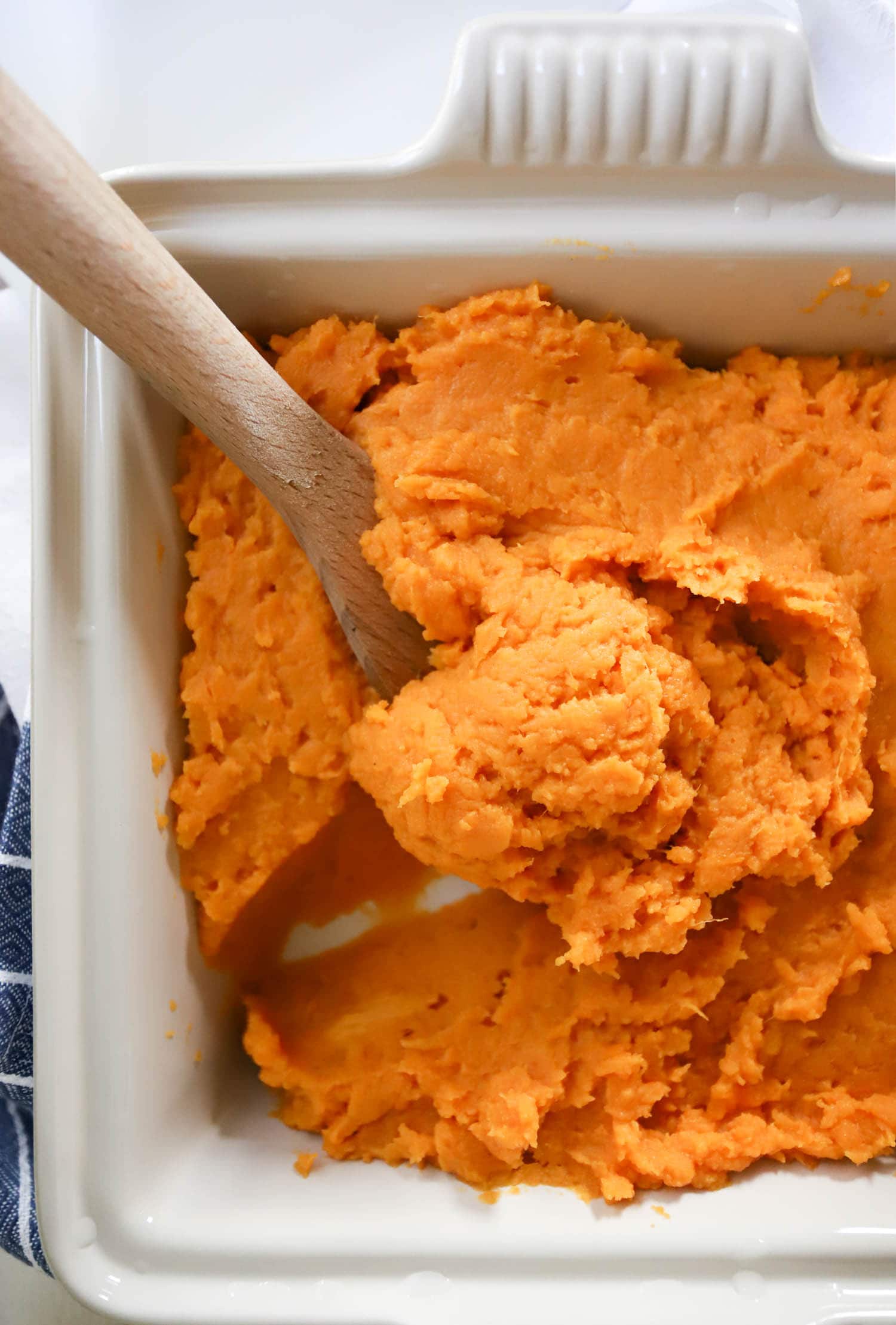 wooden spoon dipped into sweet potato casserole made in the microwave.