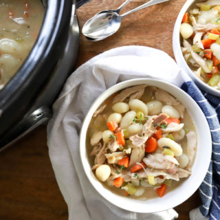 white bowl of chicken and vegetable soup with gnocchi.