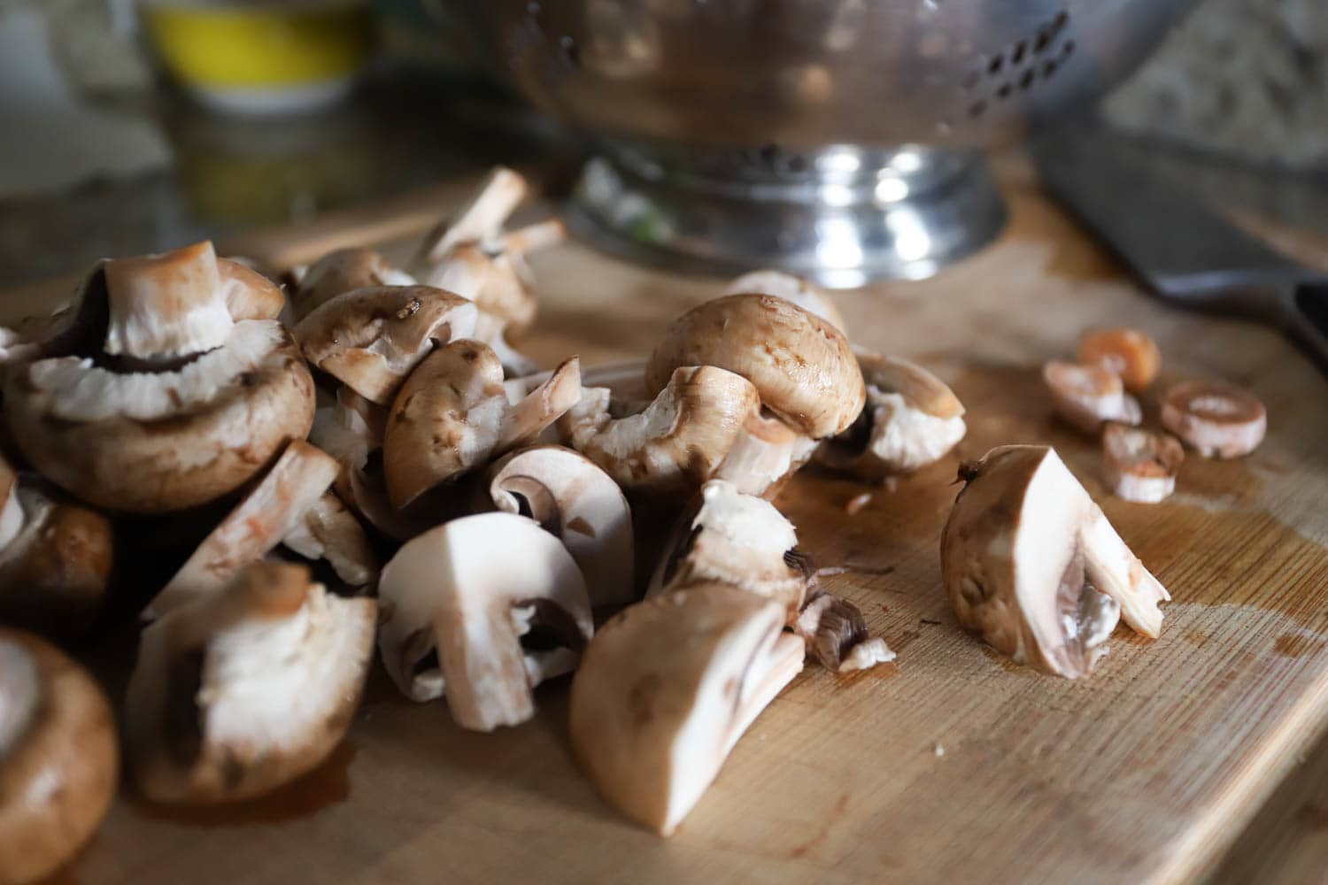 cremini mushrooms cut into quarters on cutting board.