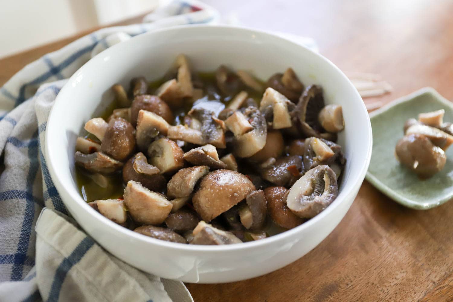 bowl of mushrooms pickled raw in white bowl with checkered napkin.