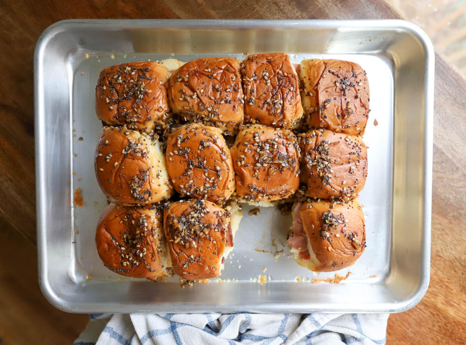 small baking sheet with grid of ham delights topped with poppy seeds.