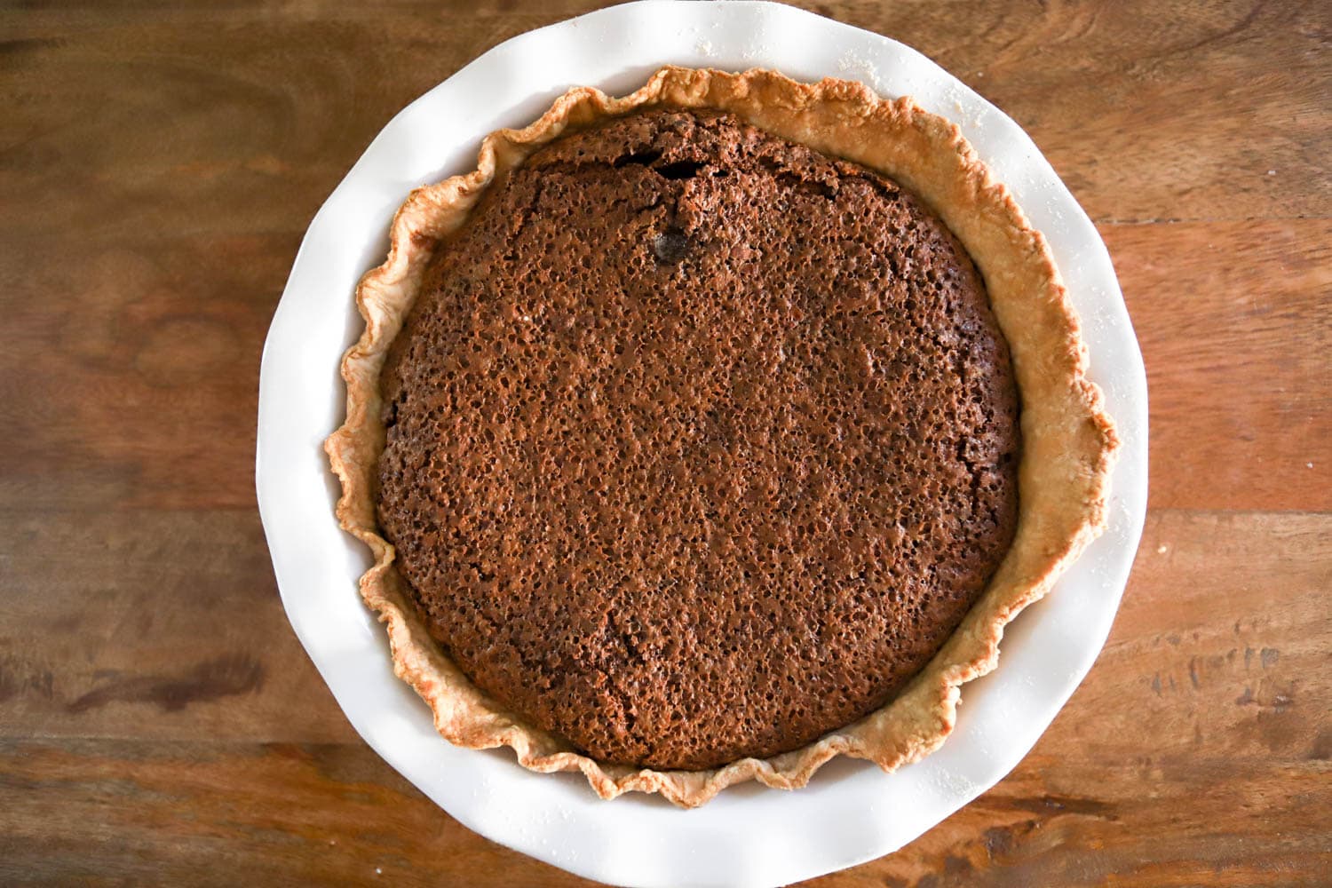 baked chocolate chess pie in white dish on wood background.