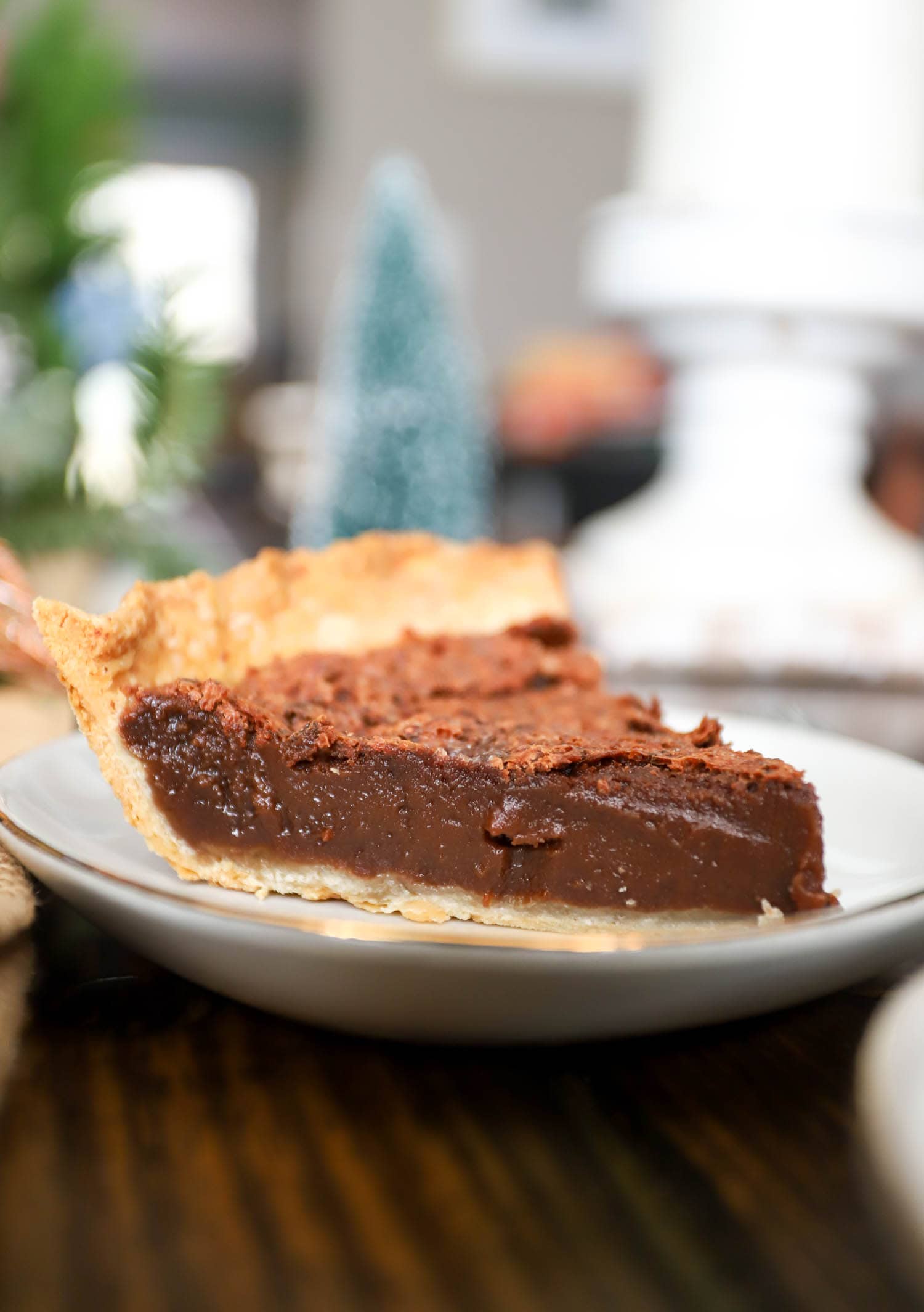 side view chocolate pie with cocoa on white and gold rimmed plate.