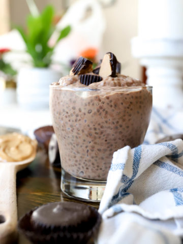 glass cup of chocolate chia pudding with flowers in the background.