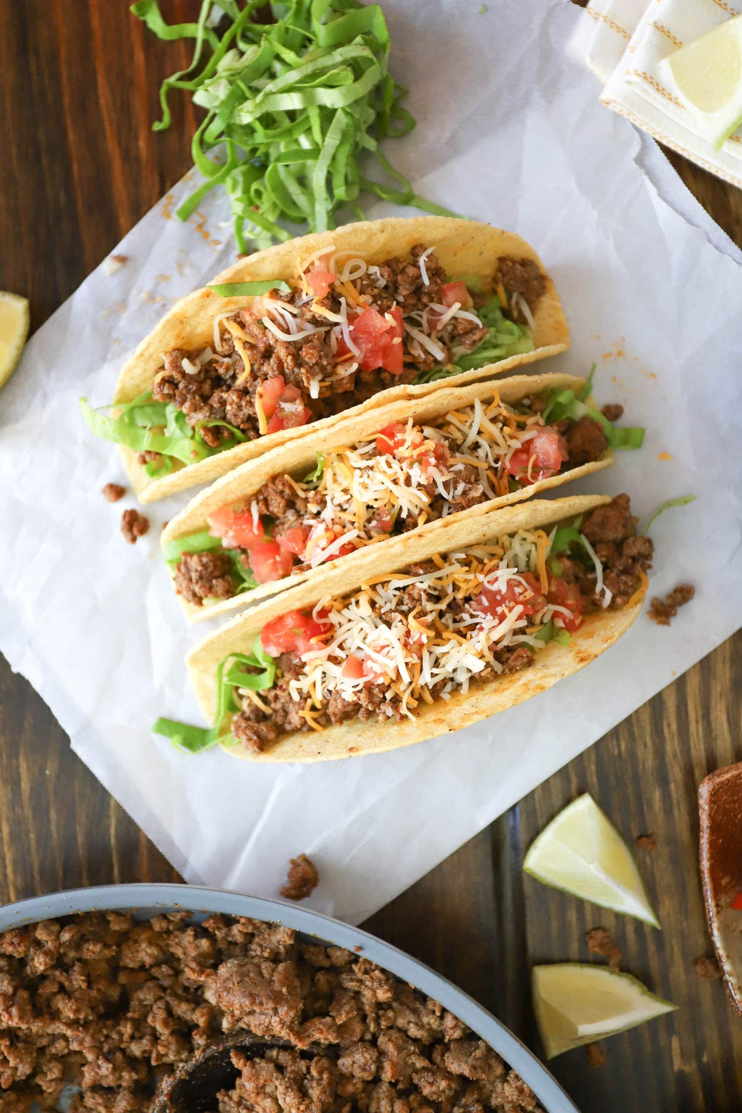 hard shall beef tacos with tomatoes and cheese on white paper.