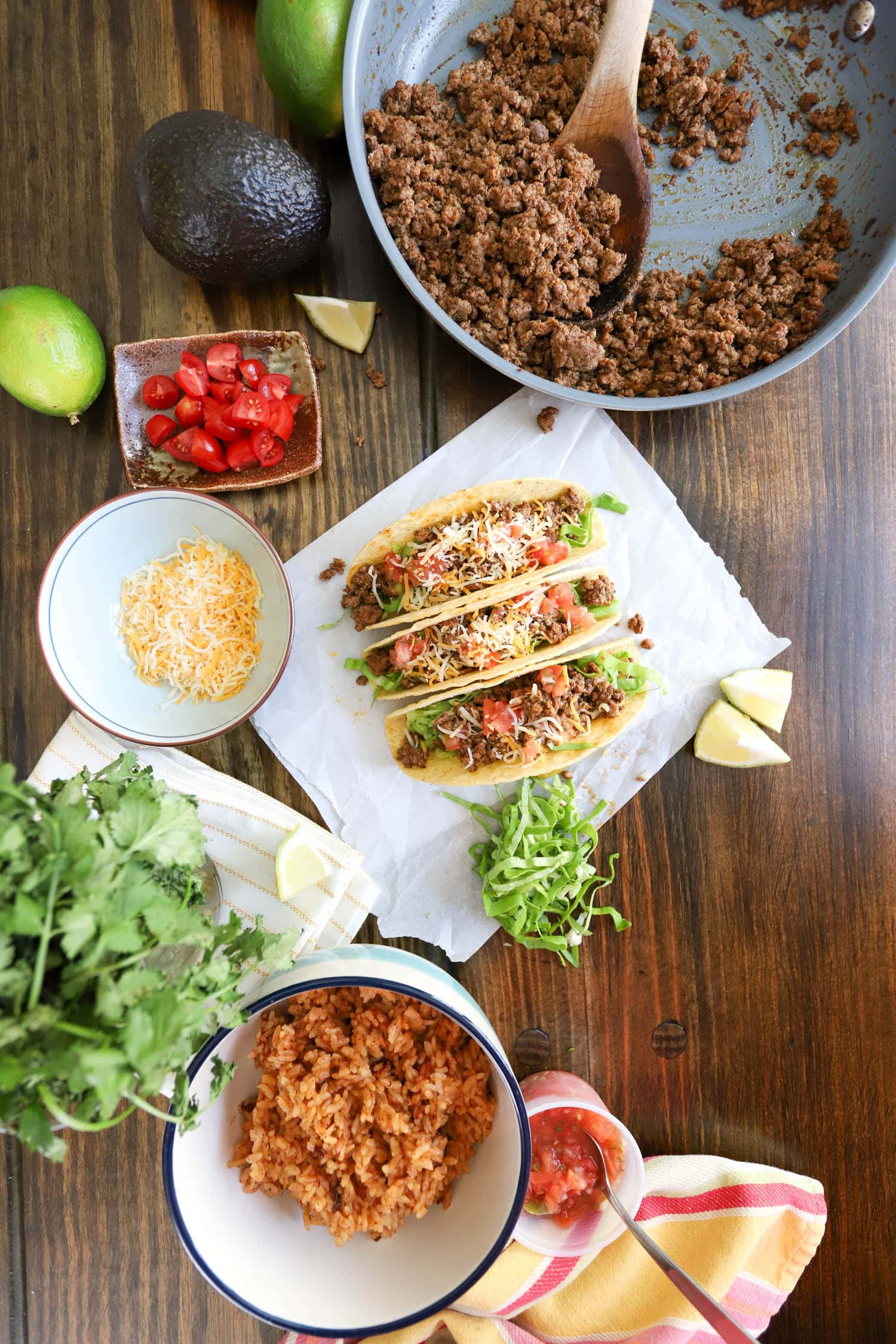 hard shall ground beef tacos spread with rice and toppings.