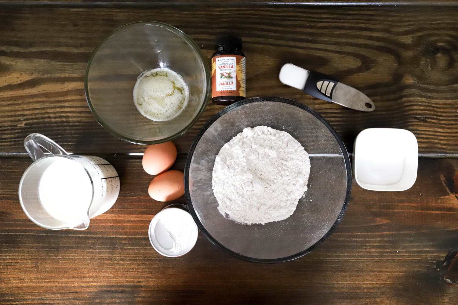 Ingredients for everyday pancakes on a brown wooden table.