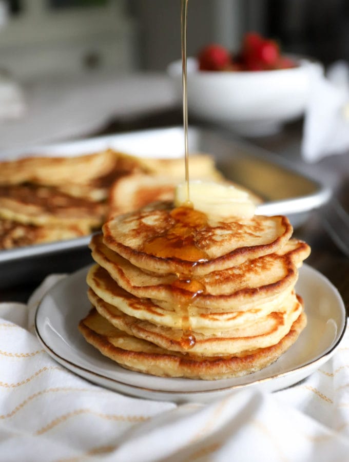 stack of pancakes with stream of syrup on white napking