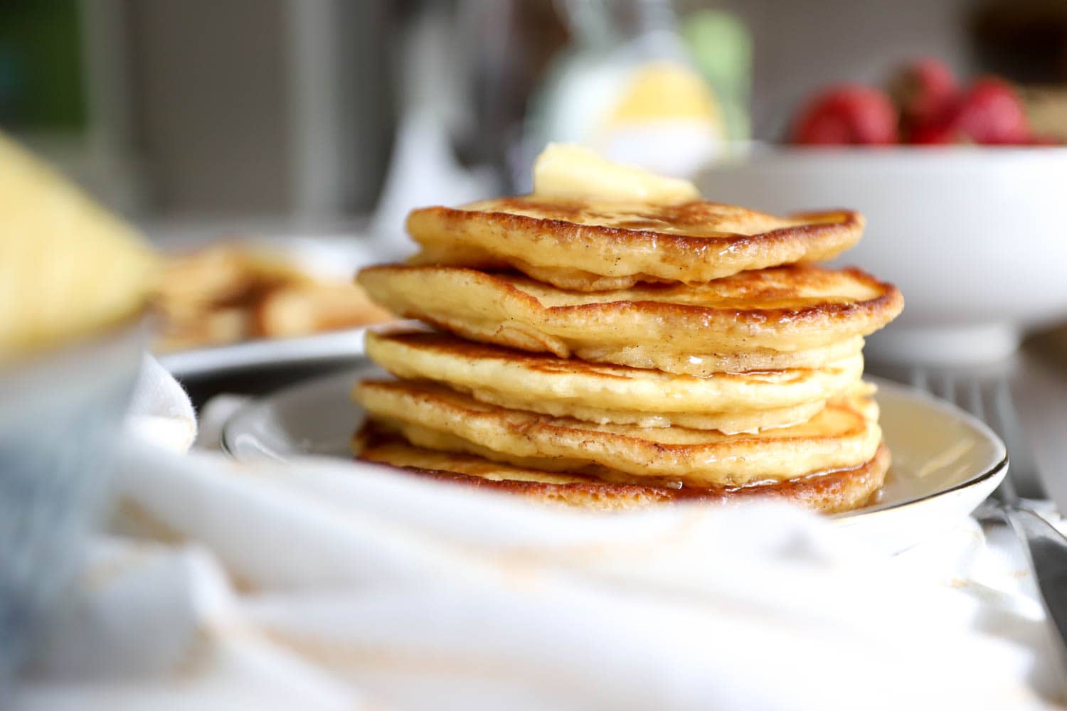 Side view of a stack of pancakes with a white cloth in the foreground.