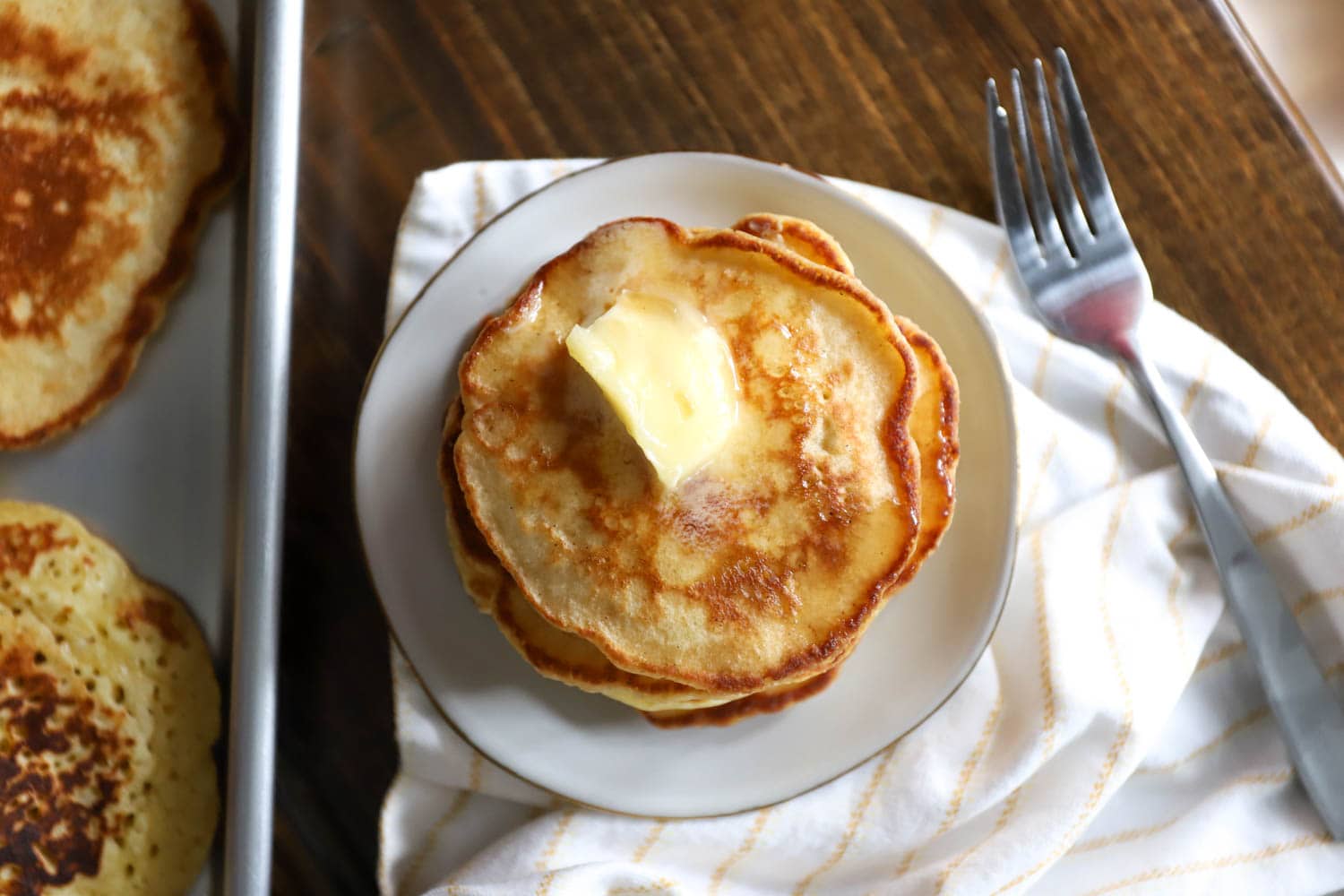 Top view of a stack of pancakes topped with butter.