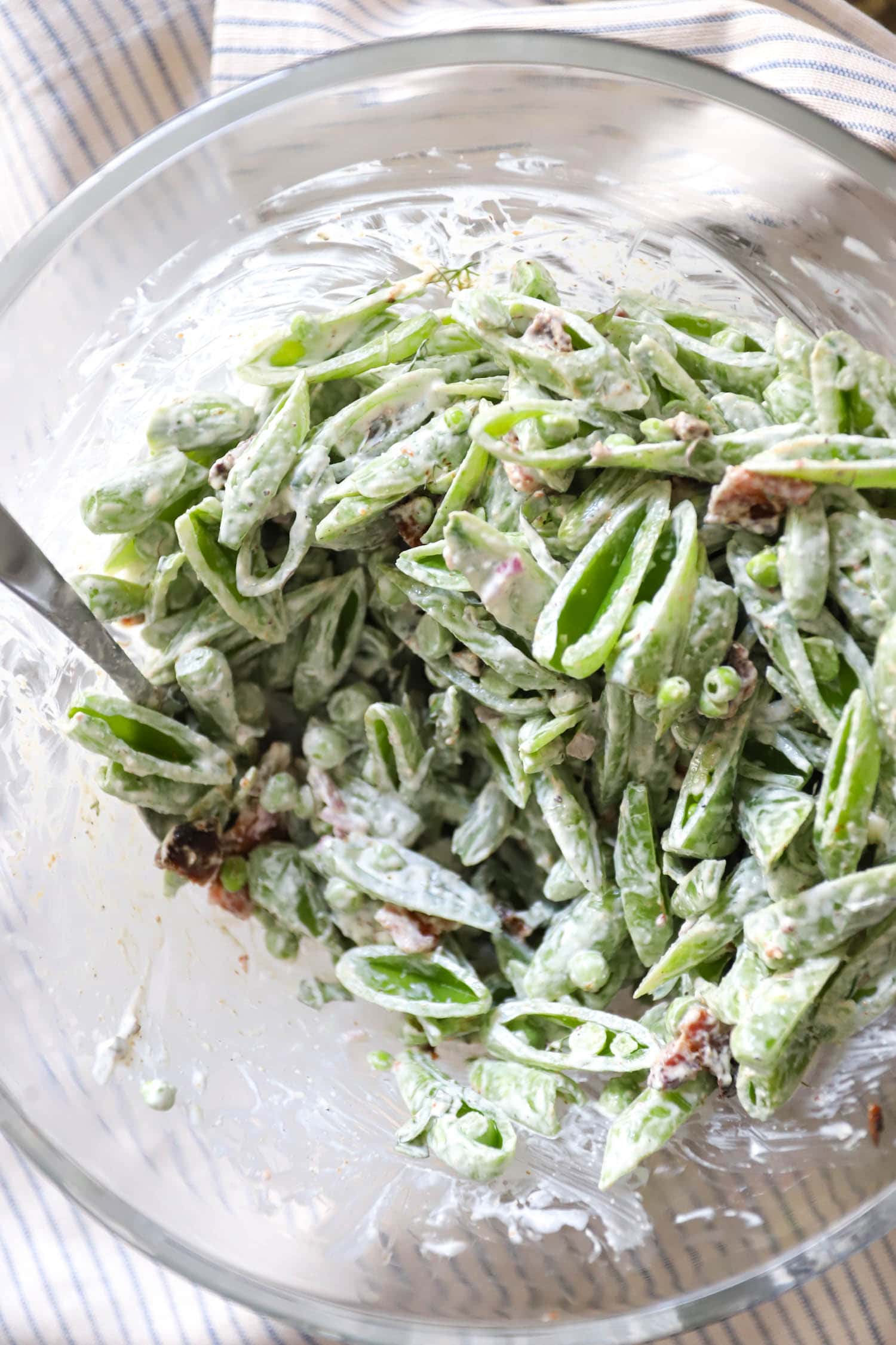 glass bowl with sugar snap pea salad and bacon.