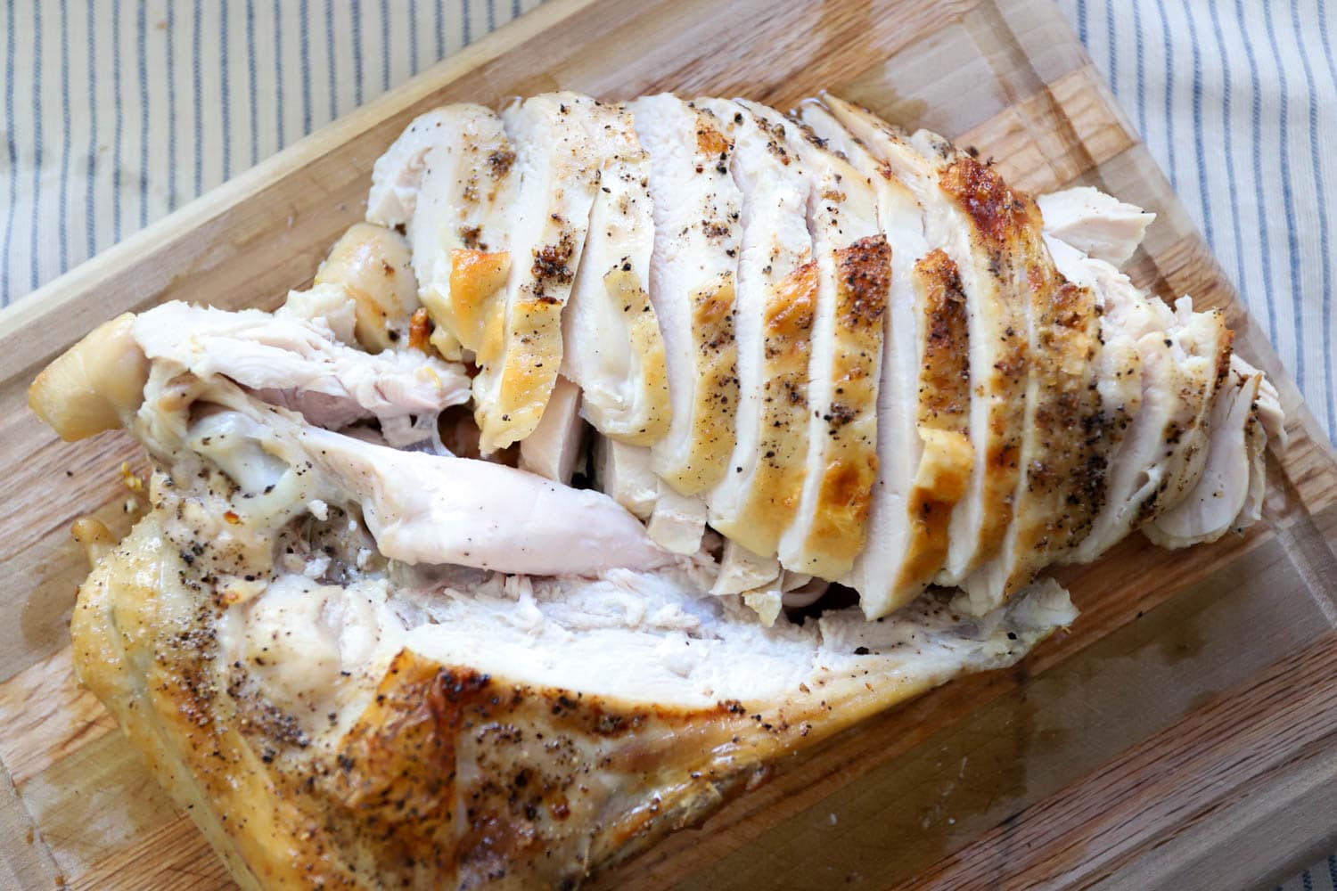 roasted turkey breast with bone sliced on wood cutting board.