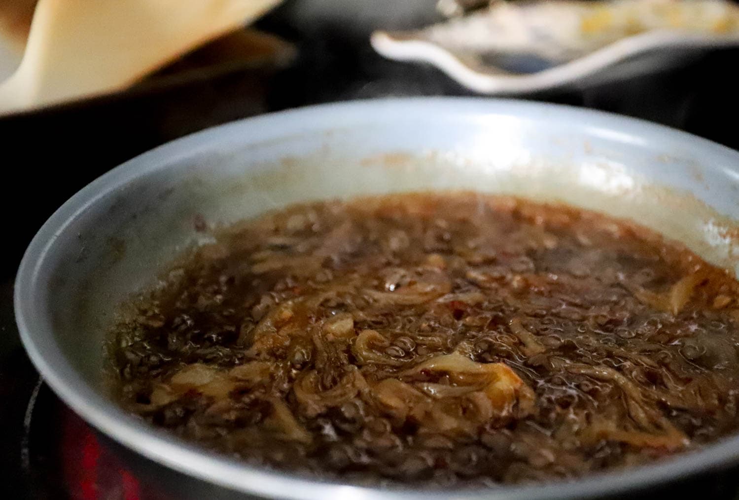 Side view skillet with bubbling caramelized onions.