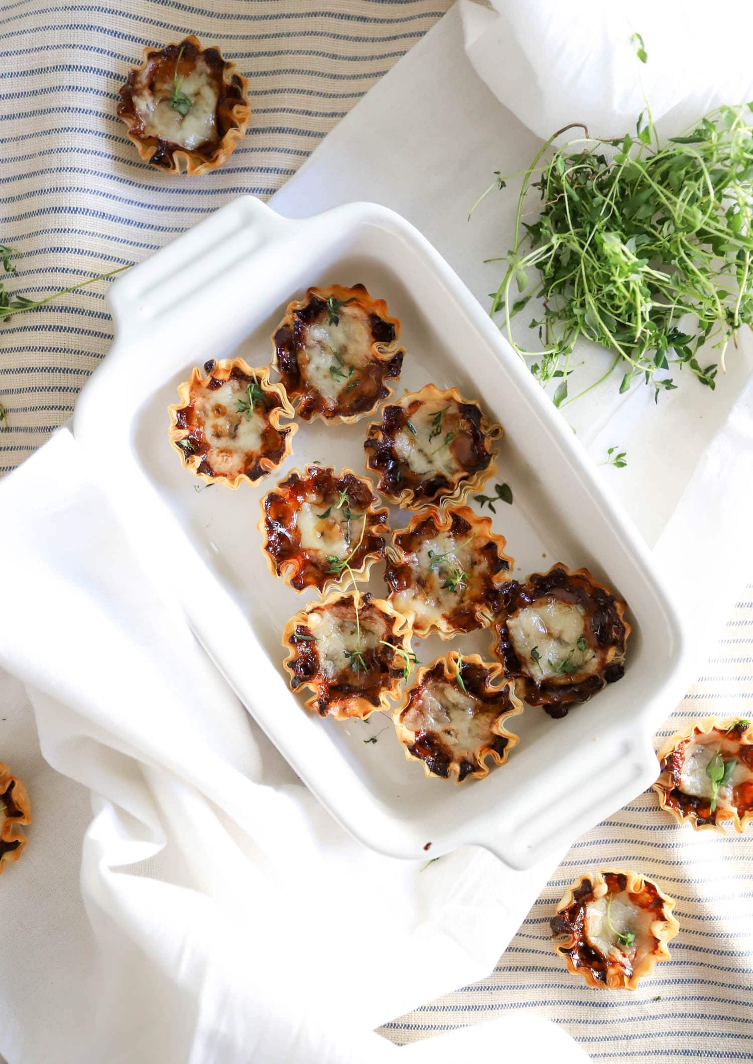 Small white baking dish with fresh thyme leaves garnishing mini French onion soup cups.