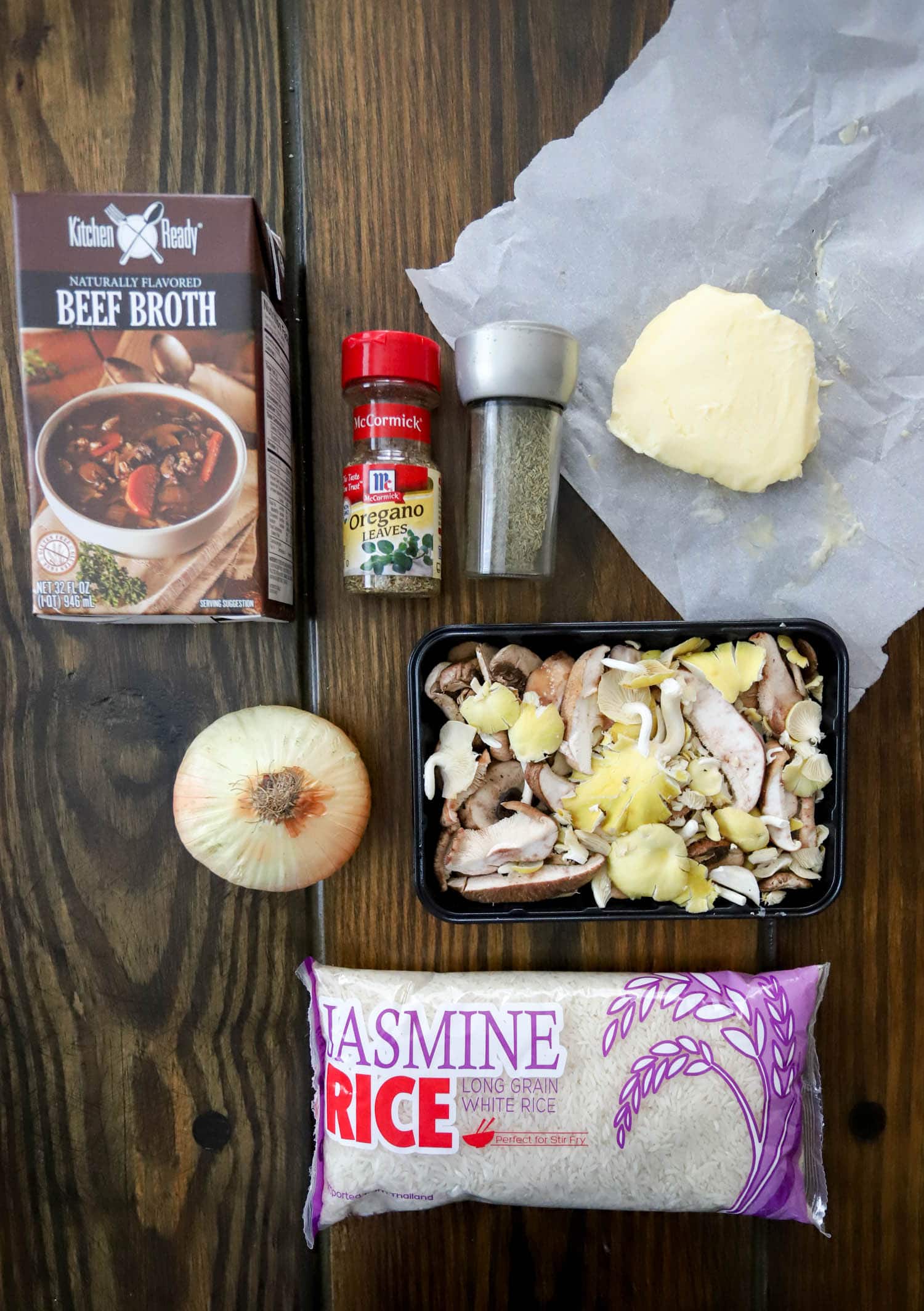 ingredients for stick of butter rice with mushrooms on a dark wood surface.