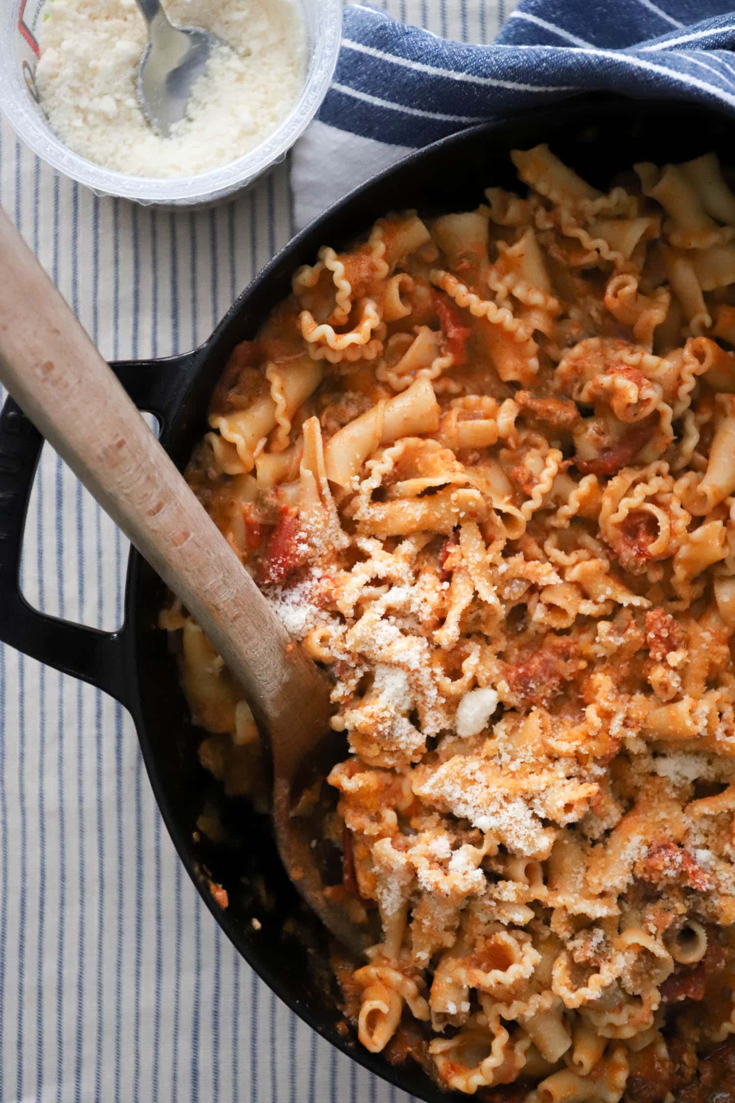 large skillet of curly pasta with parmesan and tomato sauce