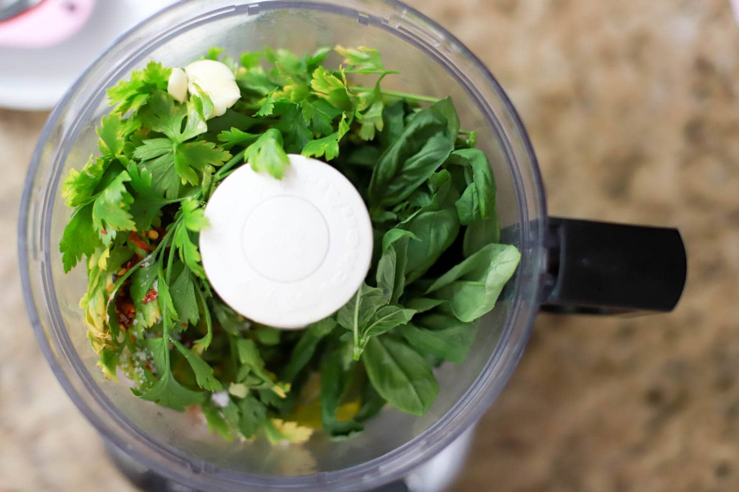 top view of food processor with basil and parsley