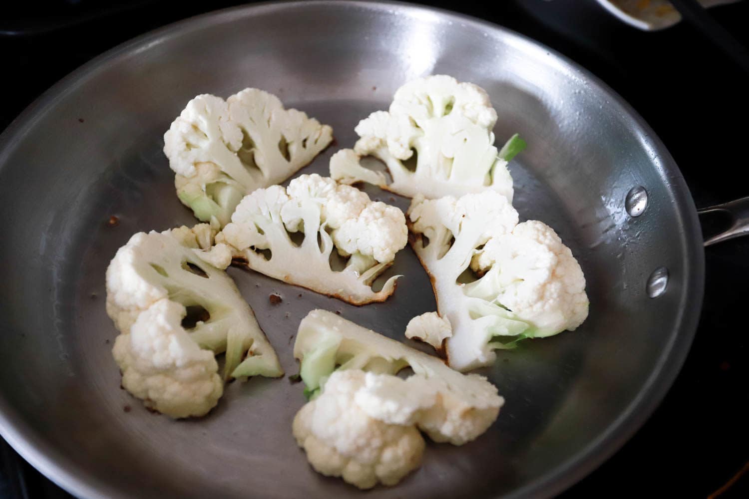 raw cauliflower searing in skillet.
