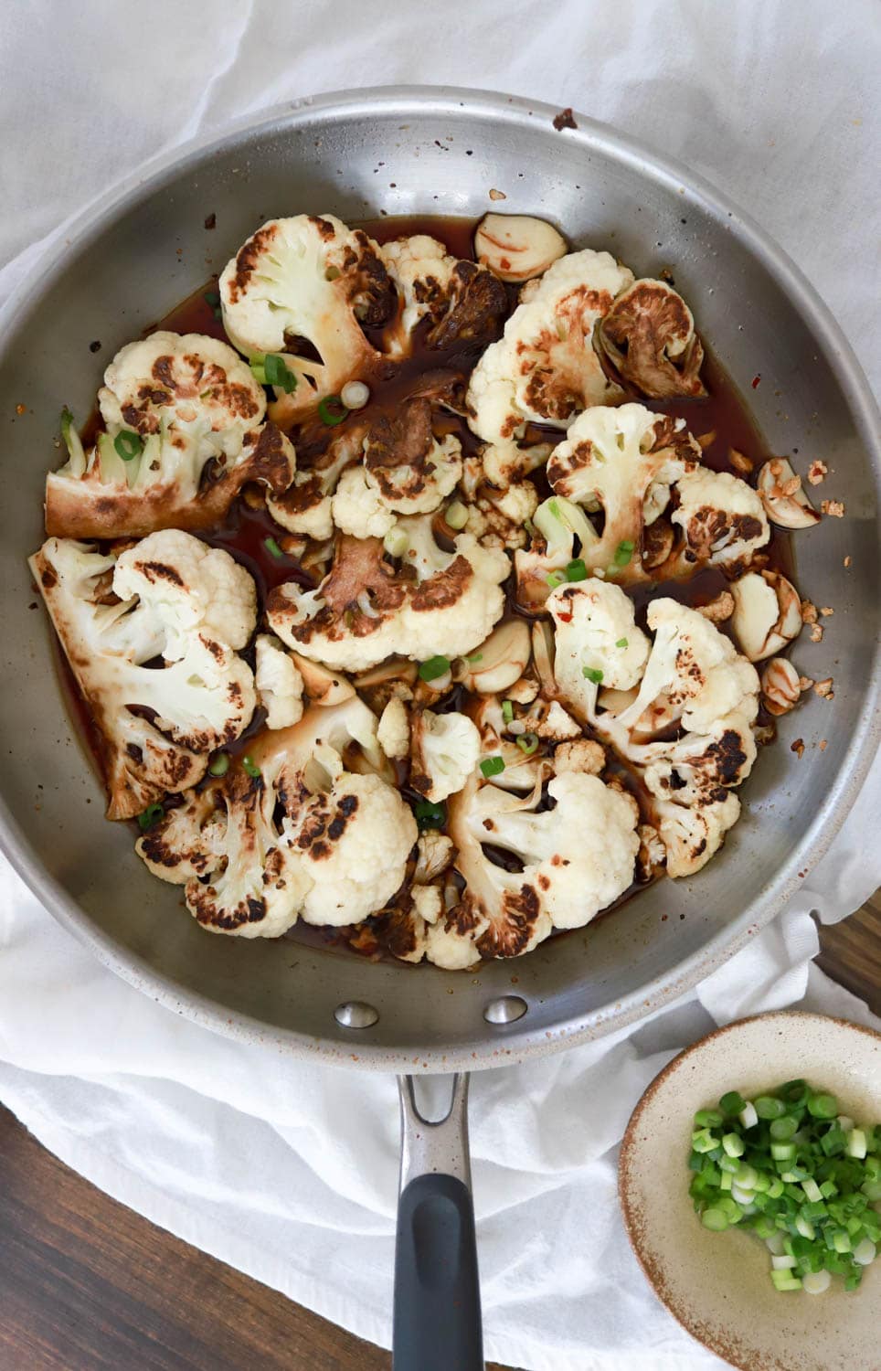 silver skillet of cauliflower adobo topped with green onions.