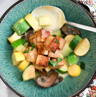 Green bowl of thai curry with zucchini squash and baked tofu.