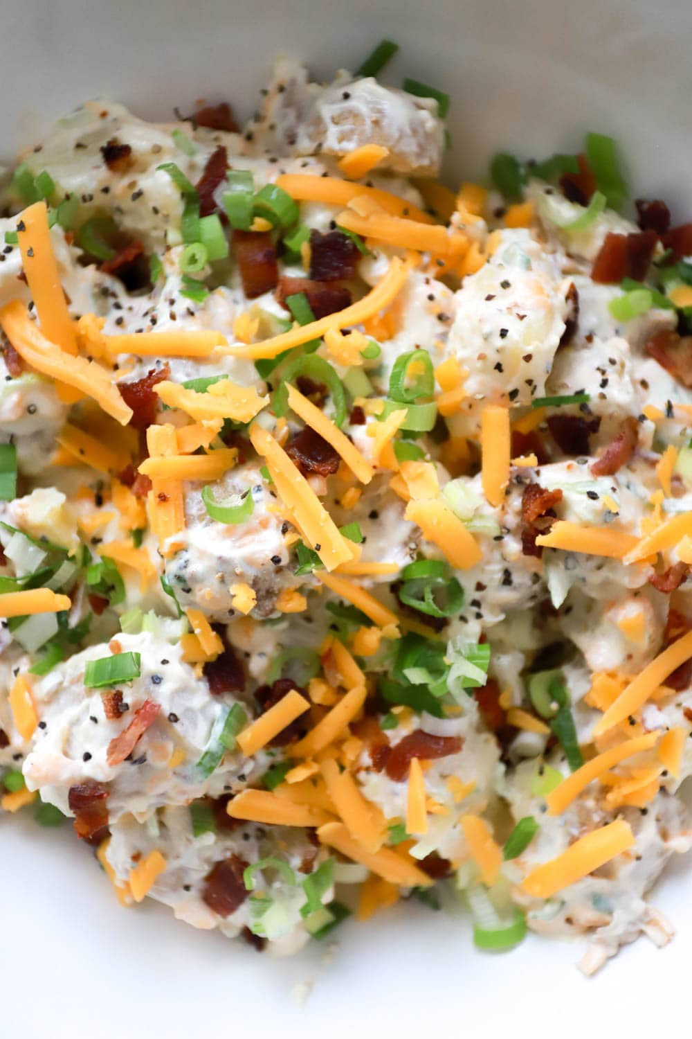 Loaded Baked Potato Salad close up image with scallions and bacon on top