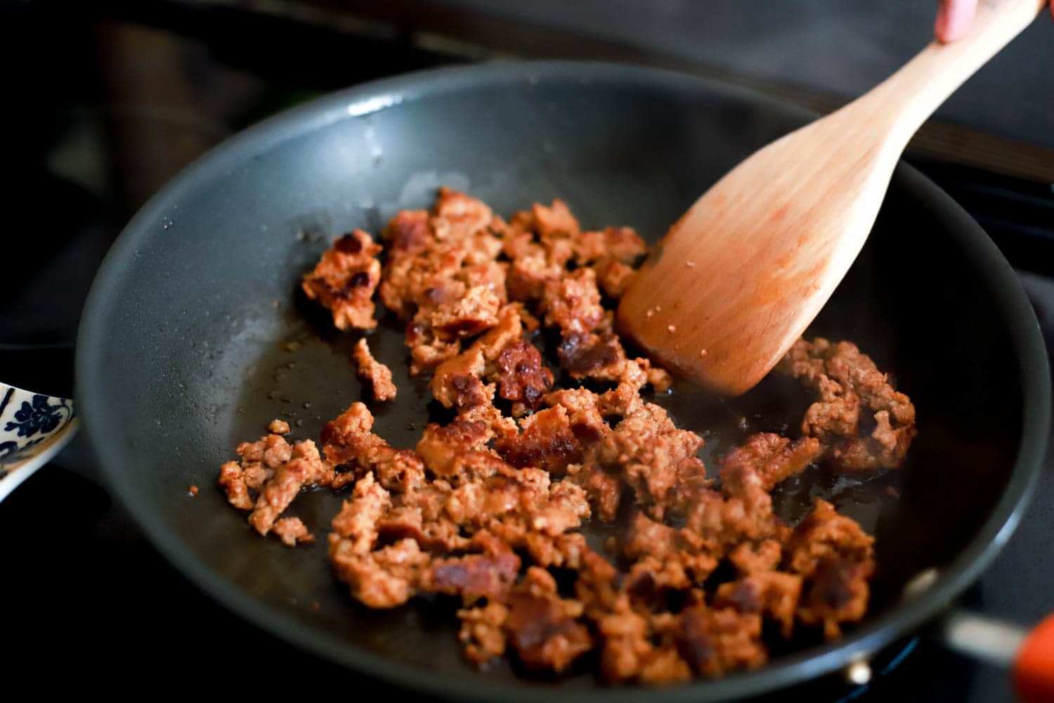 Black skillet with cooked crumbled chorizo.