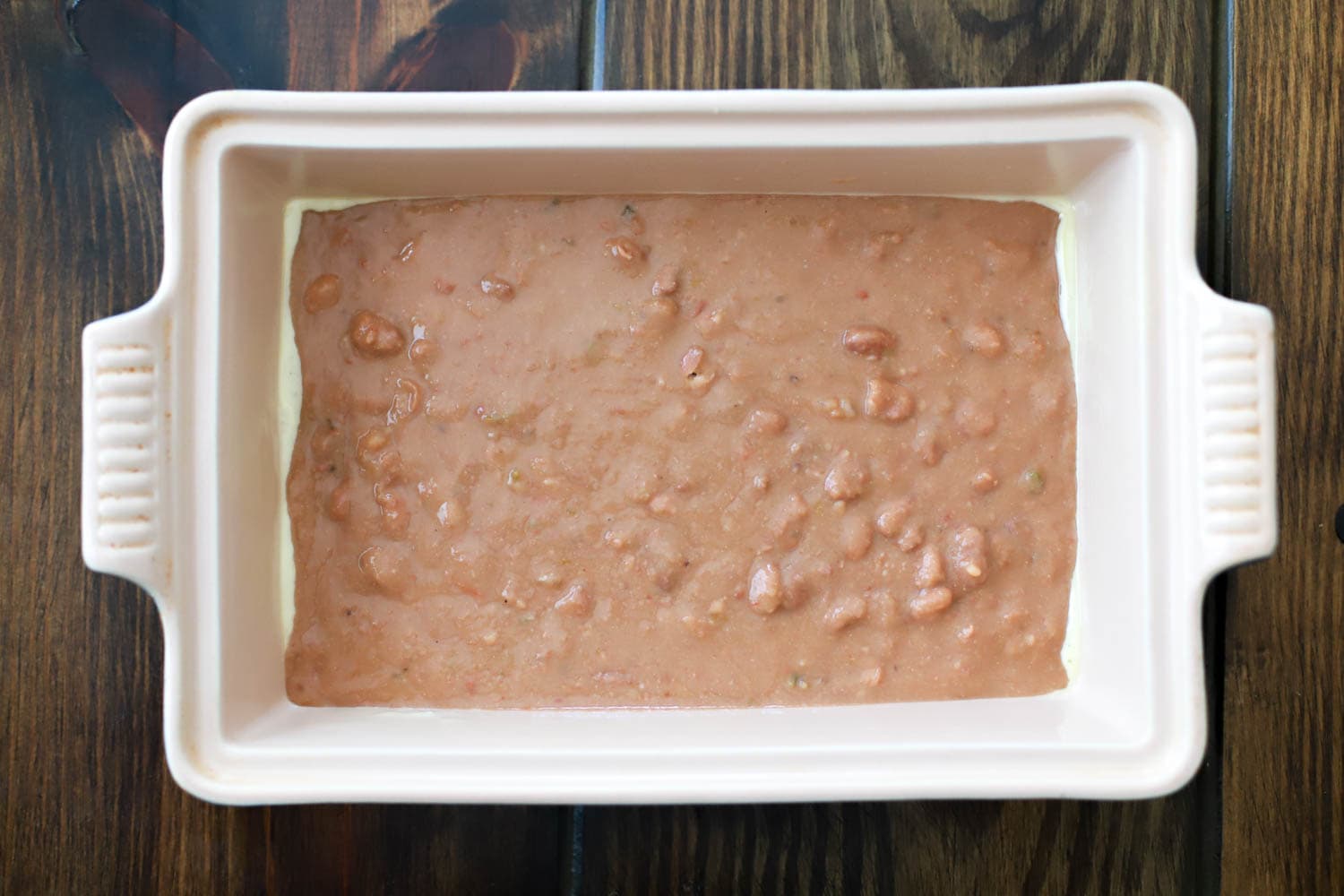 rectangular baking dish with layer of beans for dip.